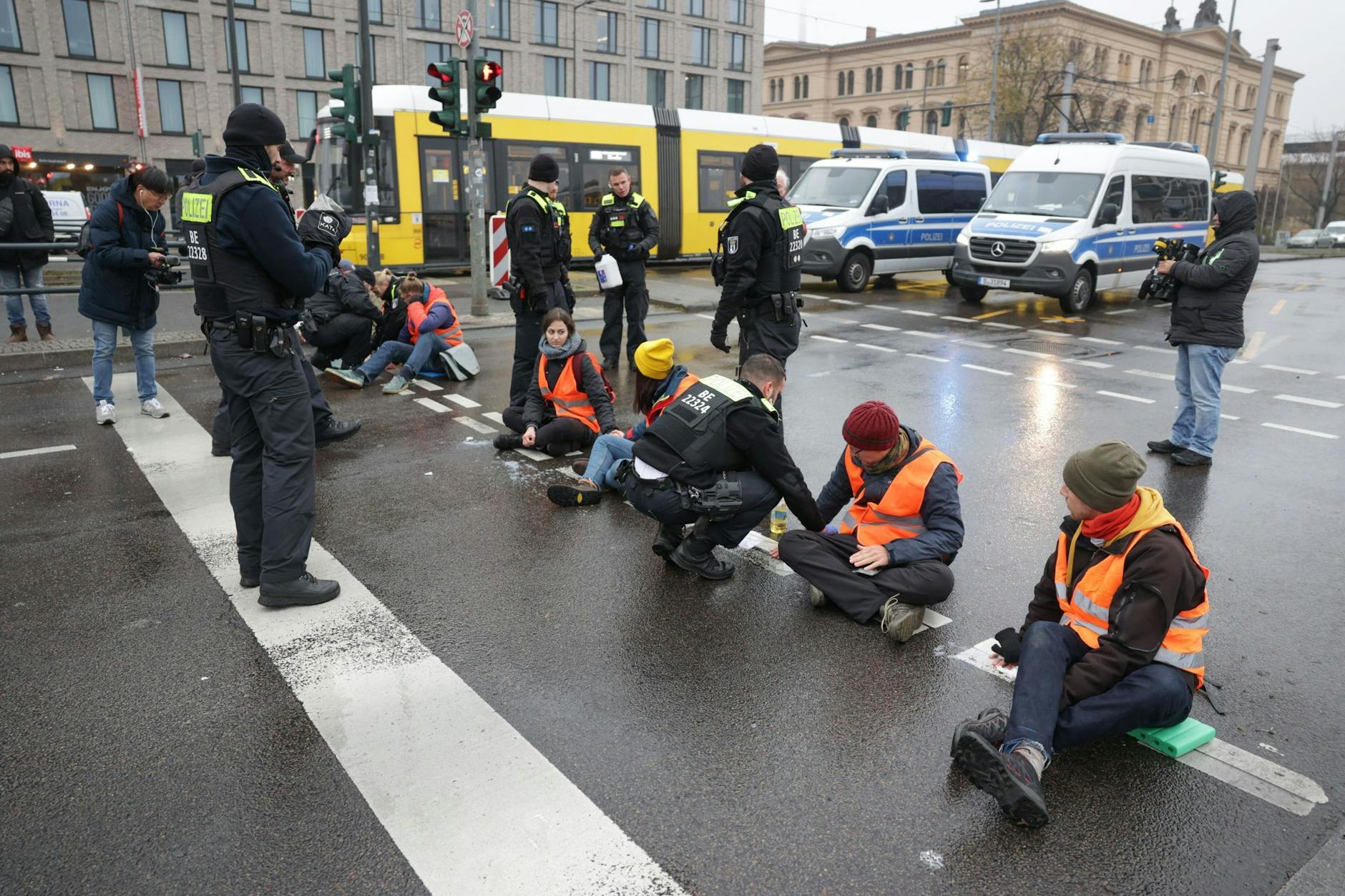 Polizisten lösen die Hand eines Klimaaktivisten vom Asphalt auf der Invalidenstraße.