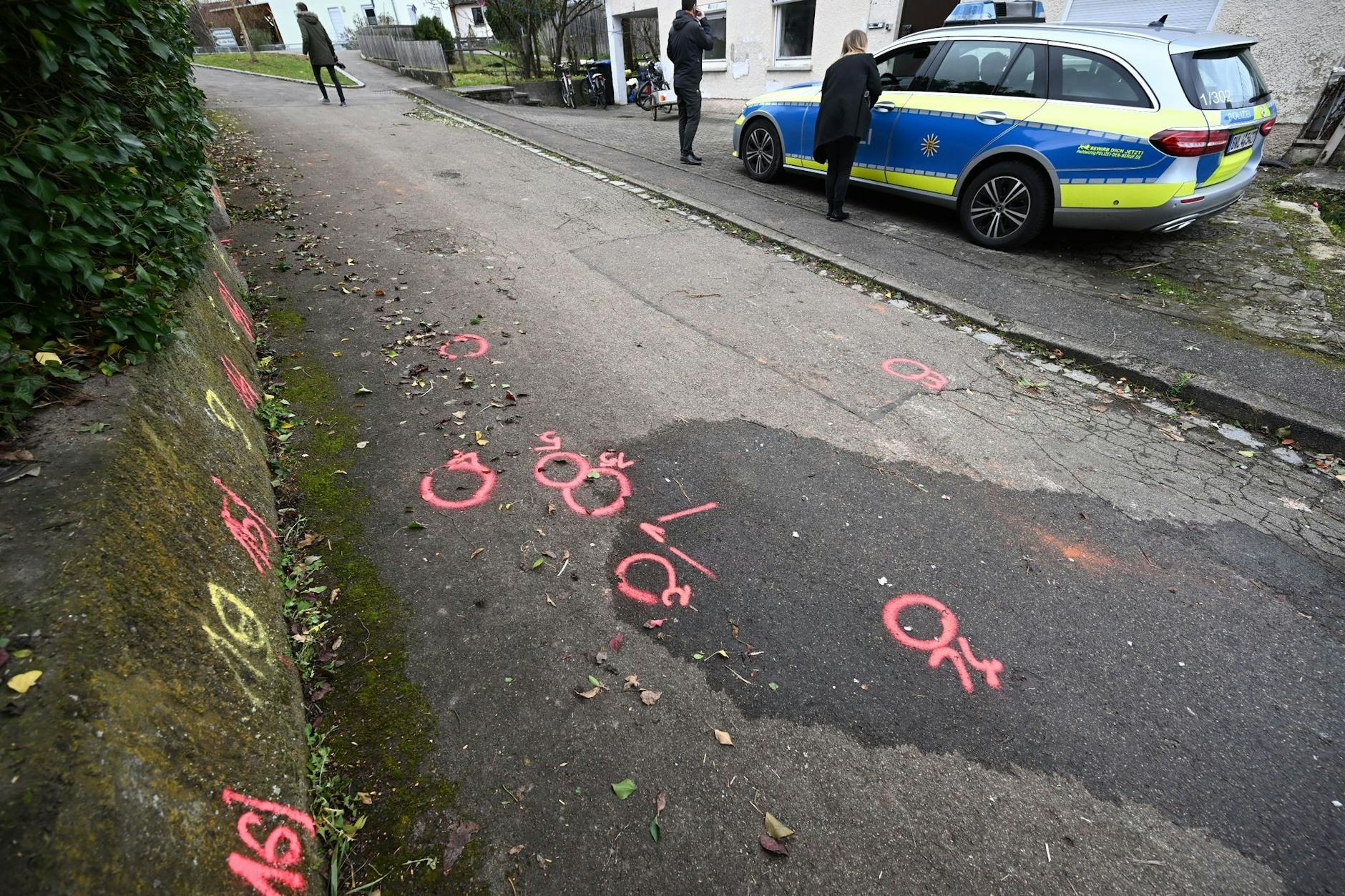 Markierungen der Spurensicherung der Polizei sind am Tatort auf einem Weg angebracht.