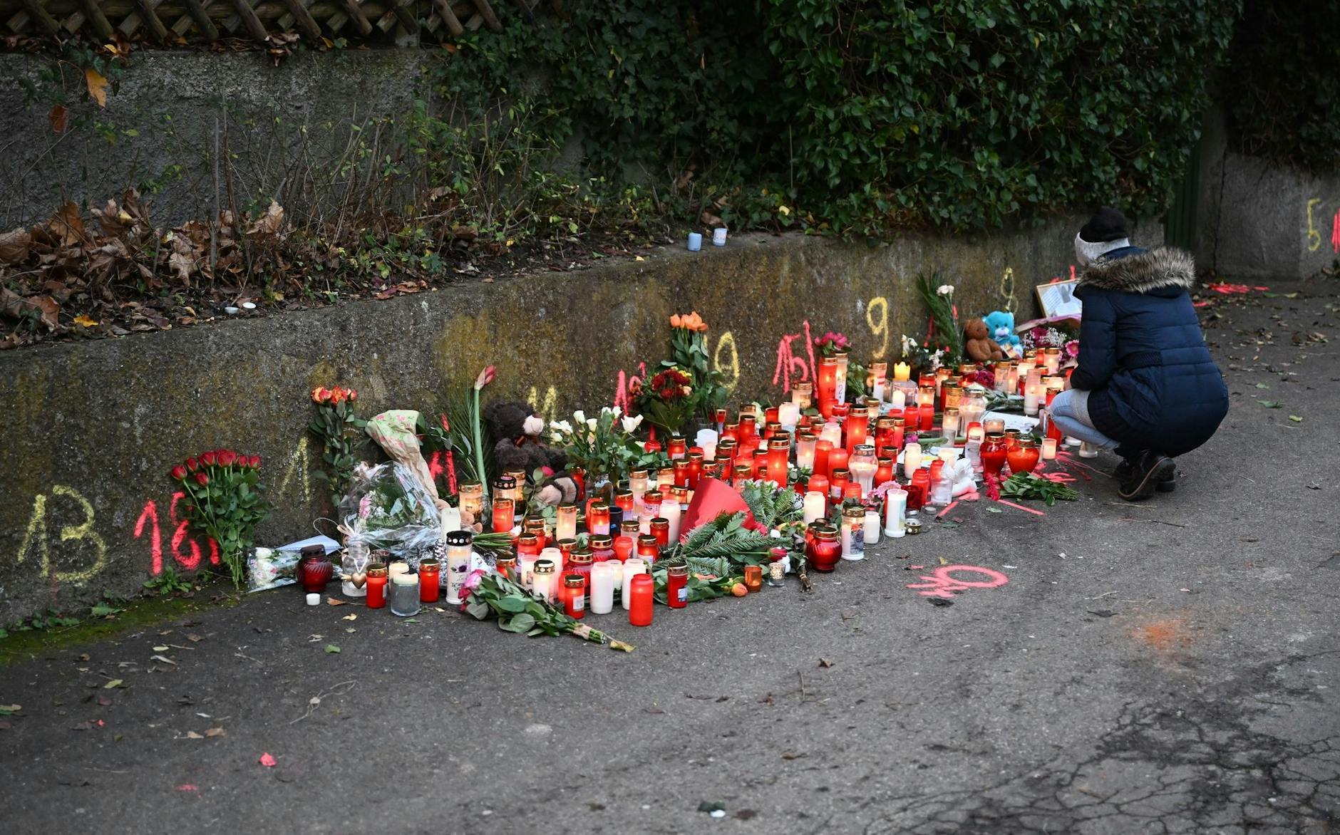 Eine Frau zündet am Tatort eines Messerangriffs eine Kerze an. Am Tag zuvor sind zwei Mädchen von einem Mann angegriffen worden, eine 14-Jährige erlag ihren schweren Verletzungen.
