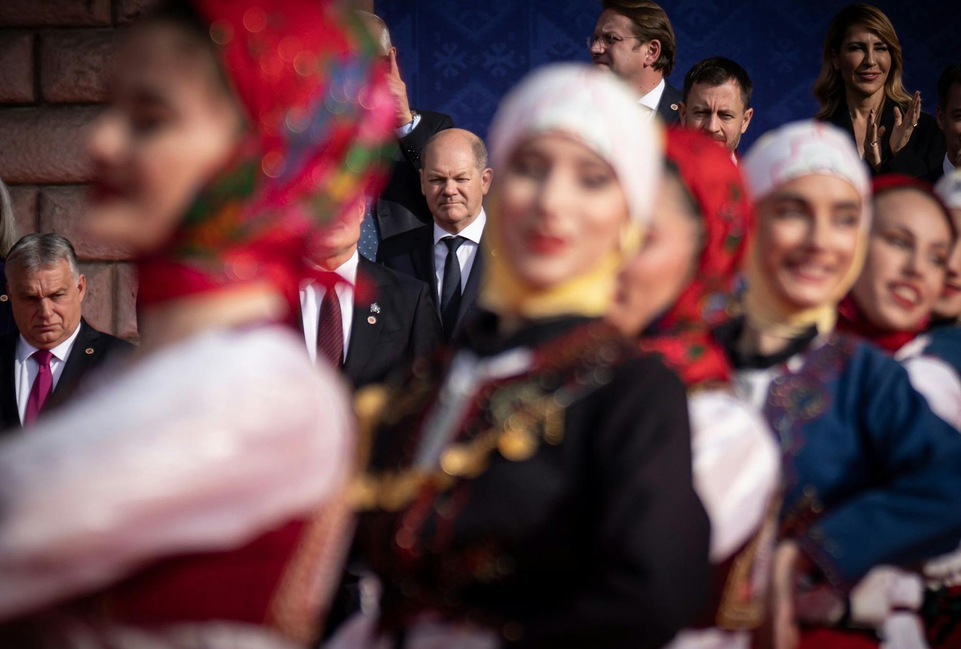 Bundeskanzler Olaf Scholz (M) beobachtet eine traditionelle Tanzvorführung beim Familienfoto beim EU-Westbalkan-Gipfel. Links ist Viktor Orban, Ministerpräsident von Ungarn, zu sehen.