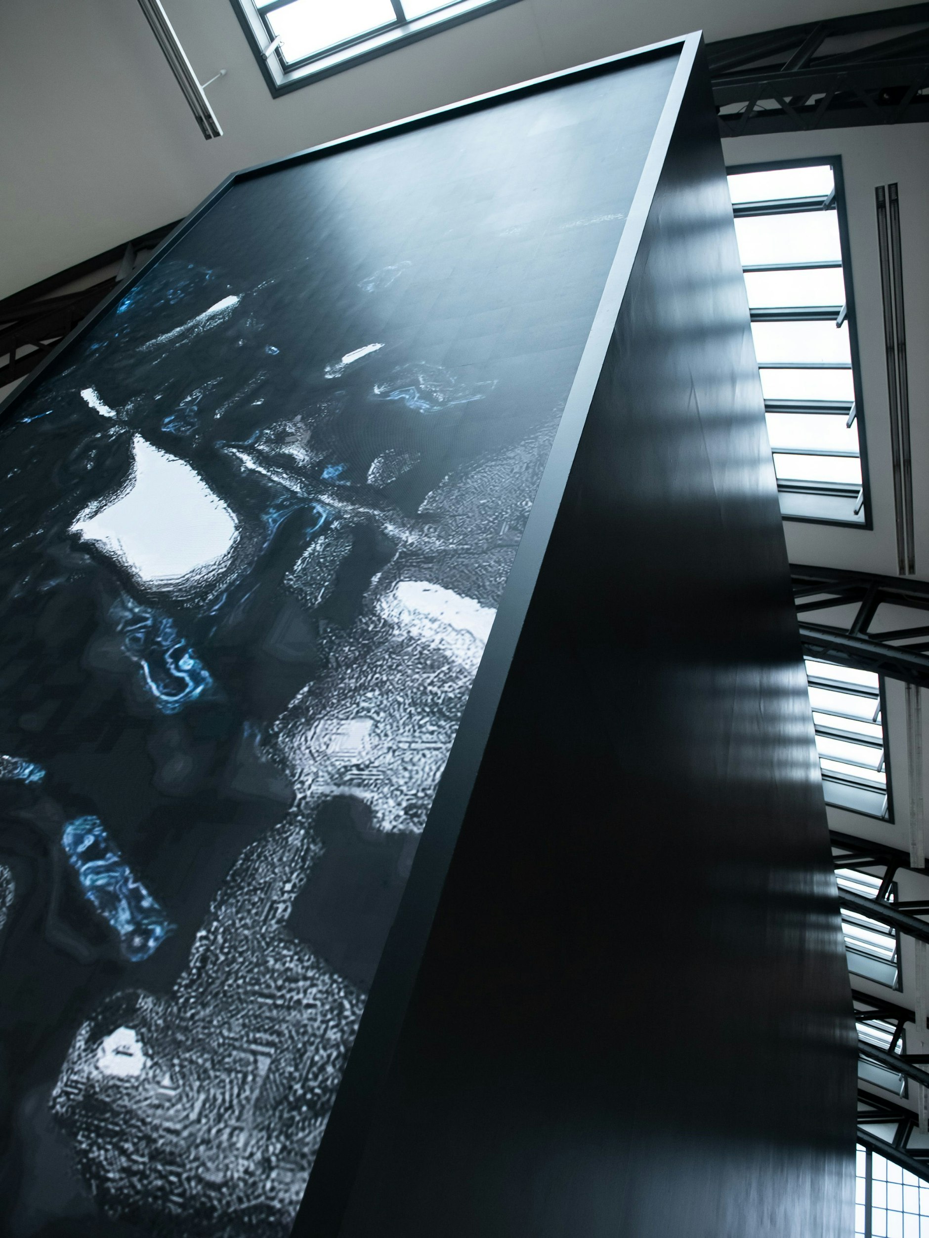 Abstrakte Videofetzen aus dem Dunkel streiten sich mit dem Oberlicht der Museumshalle.