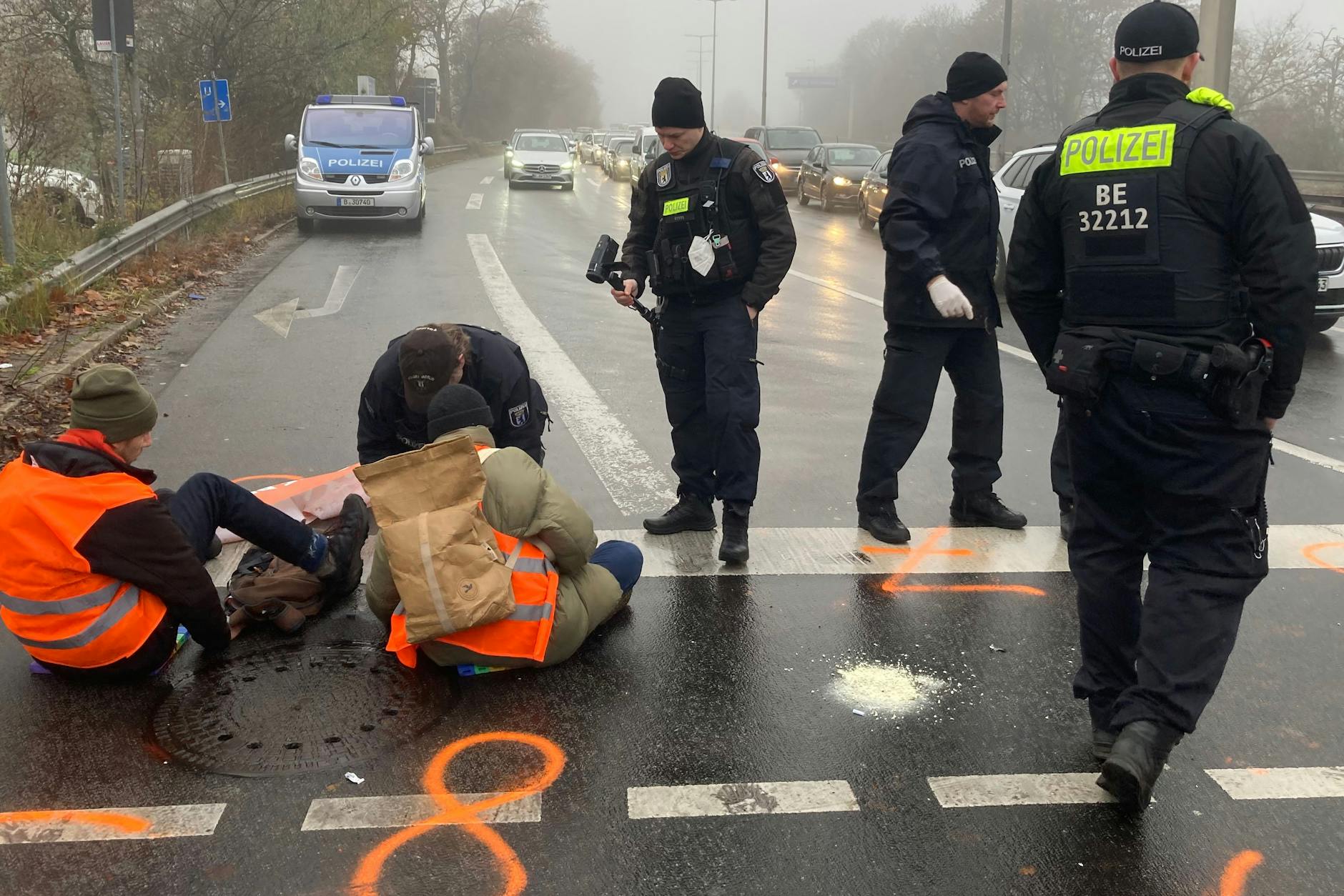Berliner Polizisten lösen Mitglieder der „Letzten Generation“ von der Fahrbahn ab, die sich zuvor dort angeklebt hatten.