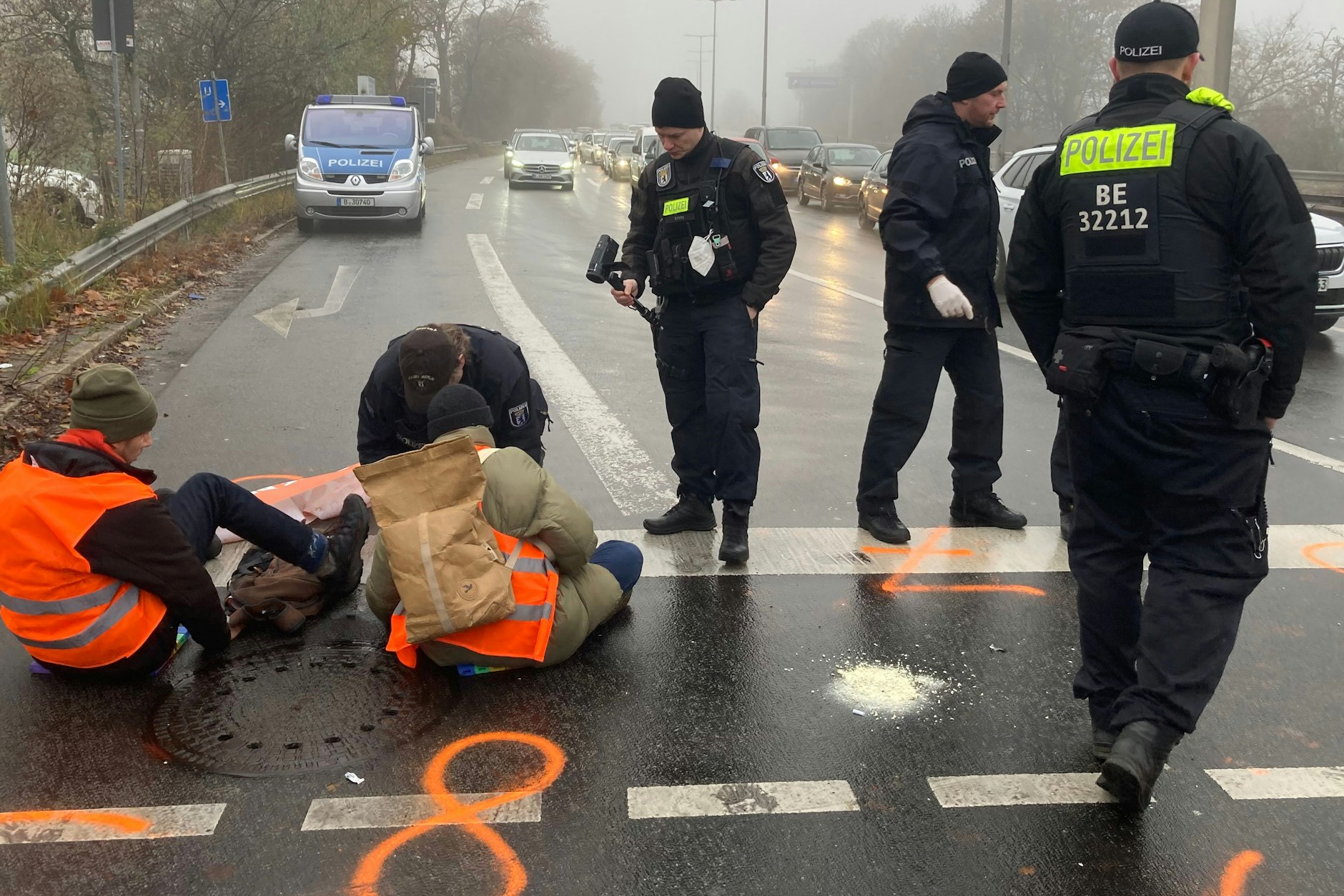 Berliner Polizisten lösen Mitglieder der „Letzten Generation“ von der Fahrbahn ab, die sich zuvor dort angeklebt hatten.