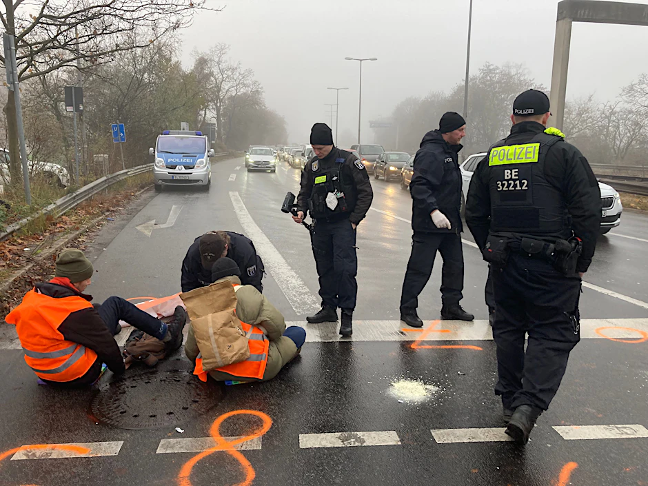 Berliner Polizisten lösen Mitglieder der „Letzten Generation“ von der Fahrbahn ab, die sich zuvor dort angeklebt hatten.