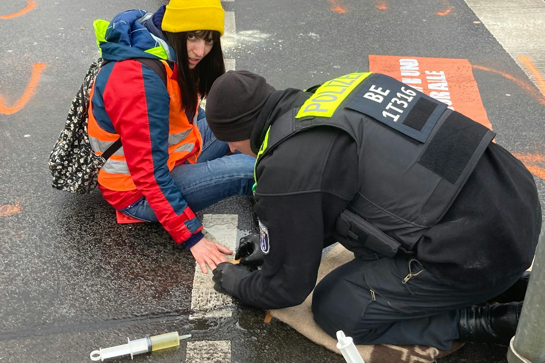 Mit Speiseöl und Holzspatel wird die Hand vom Asphalt gelöst.