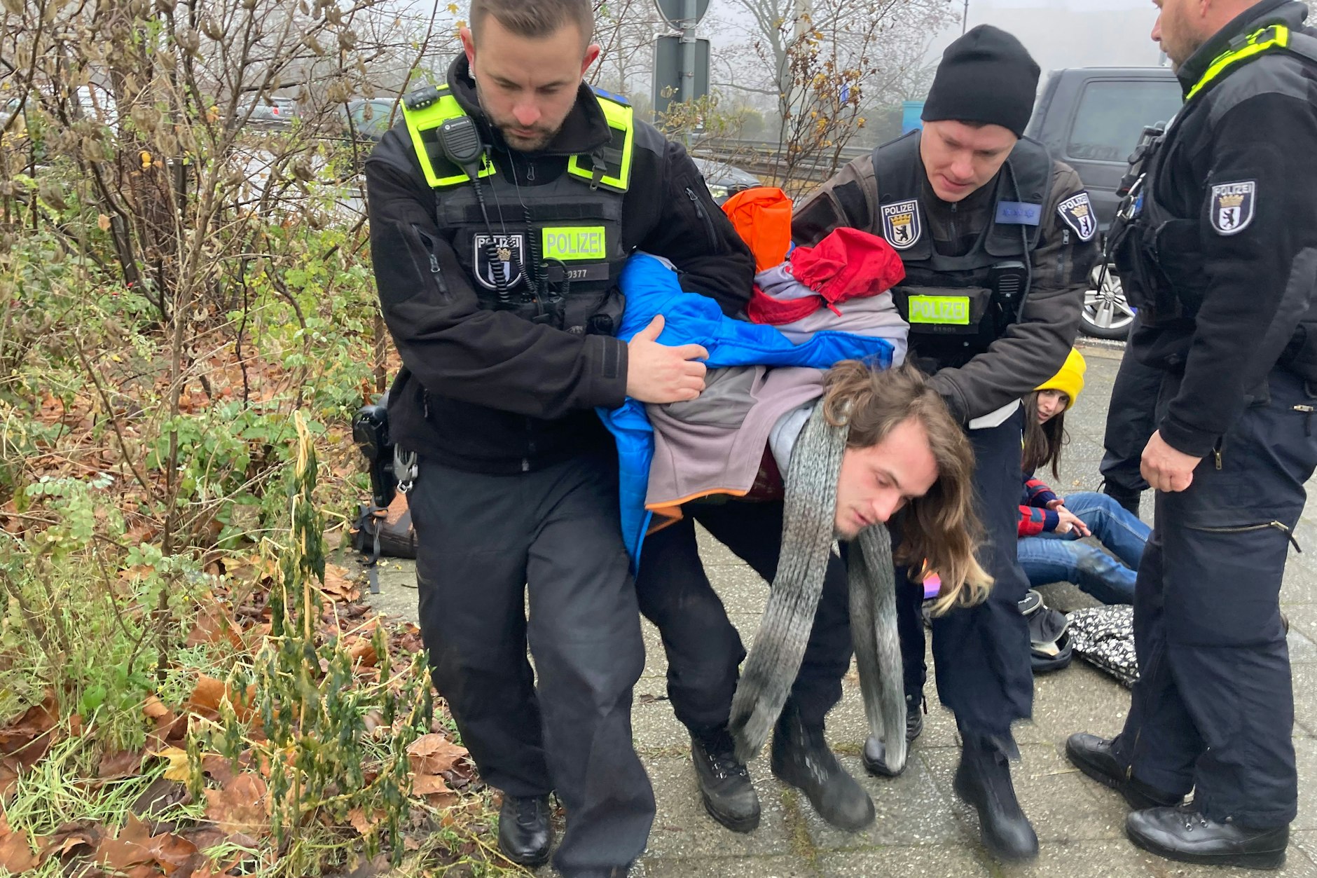 Einer der Teilnehmer wird zu einem Gefangenentransporter gebracht.