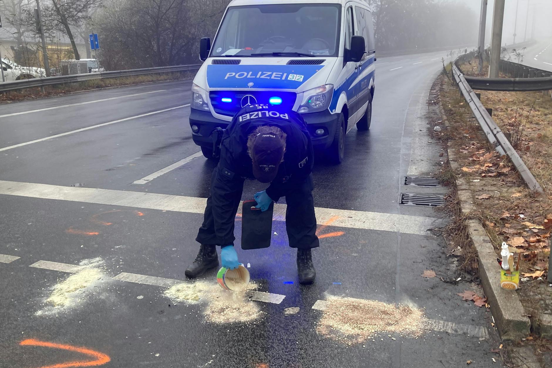 Ein Beamter kippt Bindemittel auf die Ölpfützen.