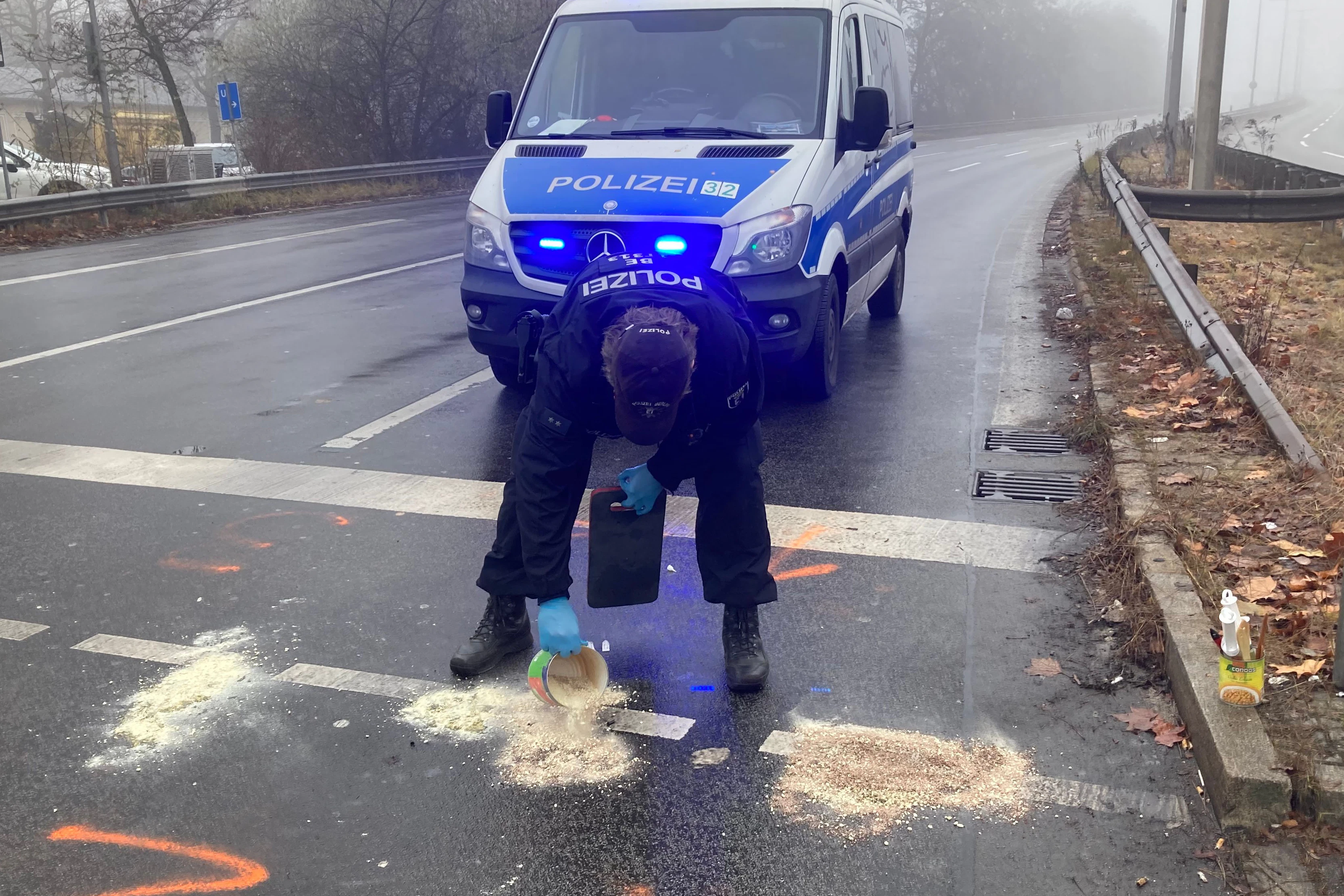 Ein Beamter kippt Bindemittel auf die Ölpfützen.
