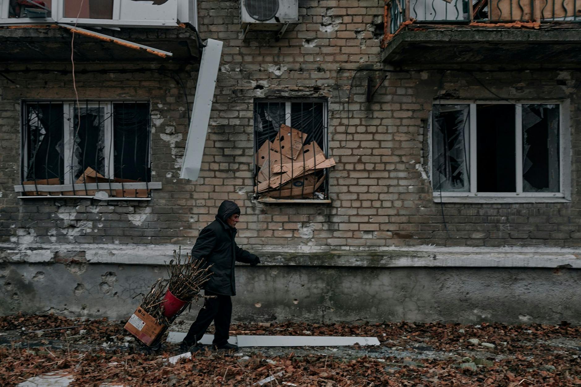 Ein Mann trägt Reisig für einen Holzofen zum Keller eines Wohnhauses im Osten der Ukraine.