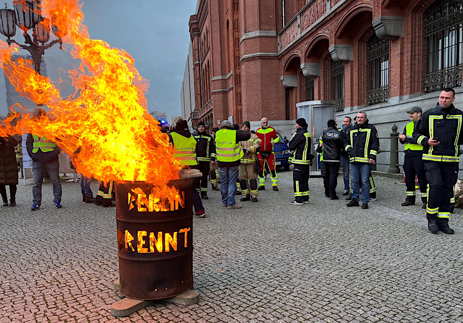 Feuerwehrleute stehen vor dem Roten Rathaus vor einer brennenden Tonne. Mit der Aktion wollen sie auf die wachsende Belastung der Behörde aufmerksam machen.&nbsp;