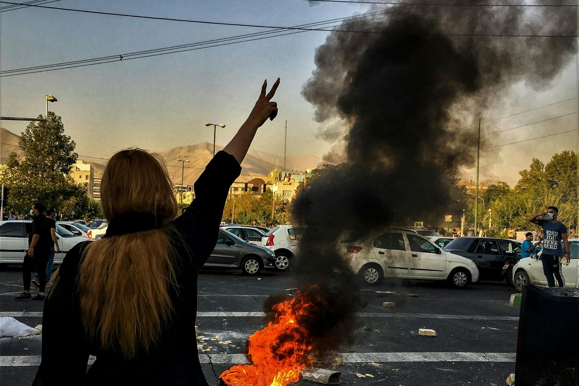 Eine Frau steht während einer Demonstration nach dem Tod der 22-jährigen Mahsa Amini vor einem brennenden Autoreifen.