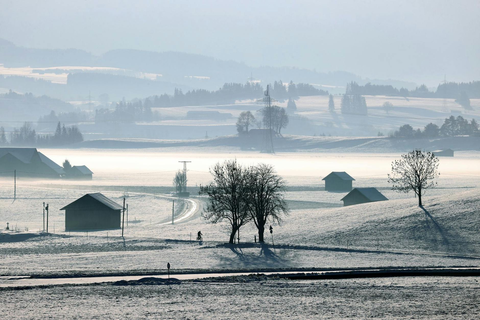 Das mit Neuschnee bedeckte und im Morgendunst liegende Voralpenland.