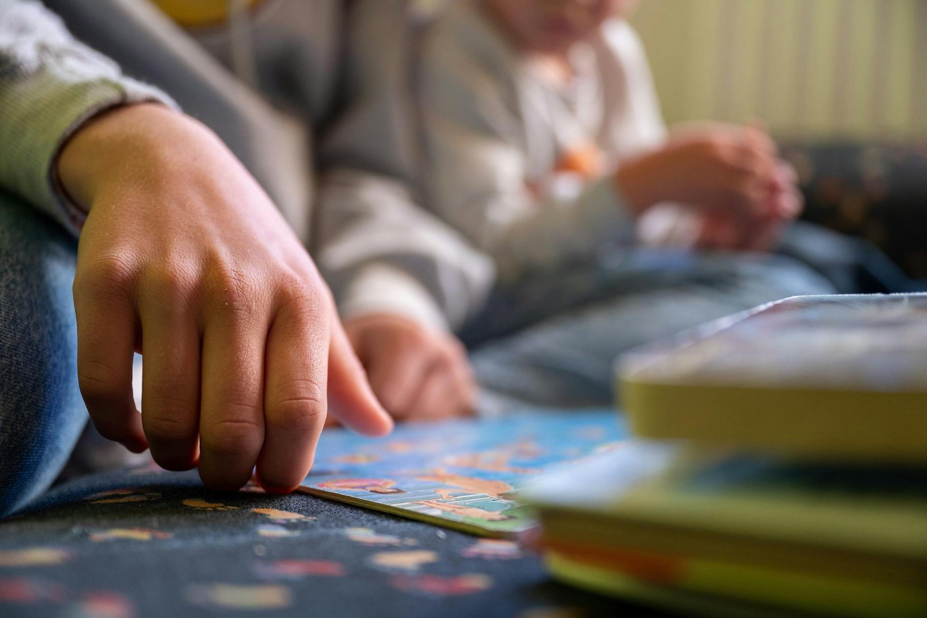 Eine Erzieherin schaut mit einem Kind in der Kita ein Bilderbuch an. Sich für einzelne Kinder Zeit zu nehmen, wird aufgrund des Personalmangels immer schwieriger.