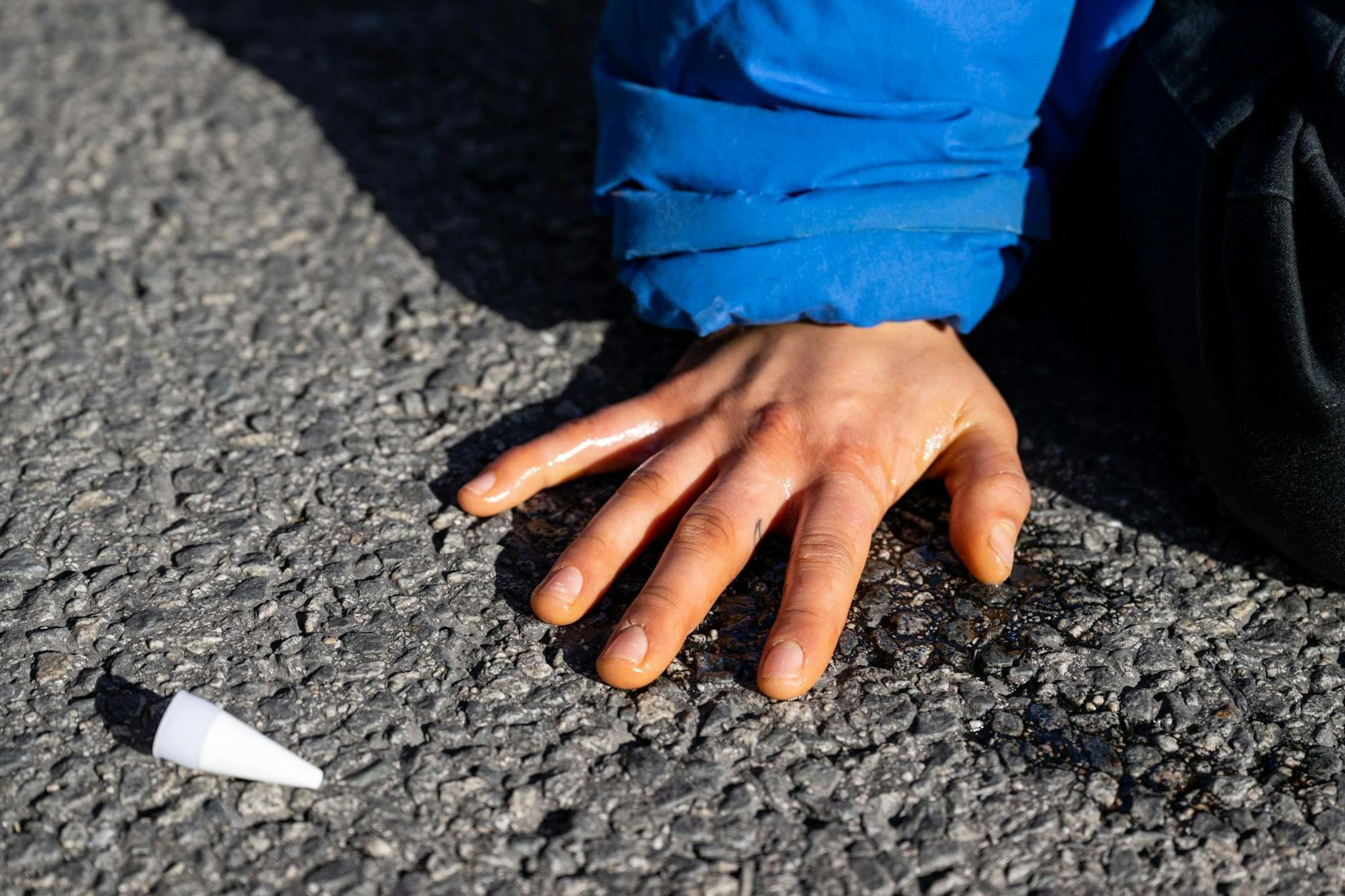 ARCHIV - Ein Klimaaktivist hat sich auf einer Straße festgeklebt.