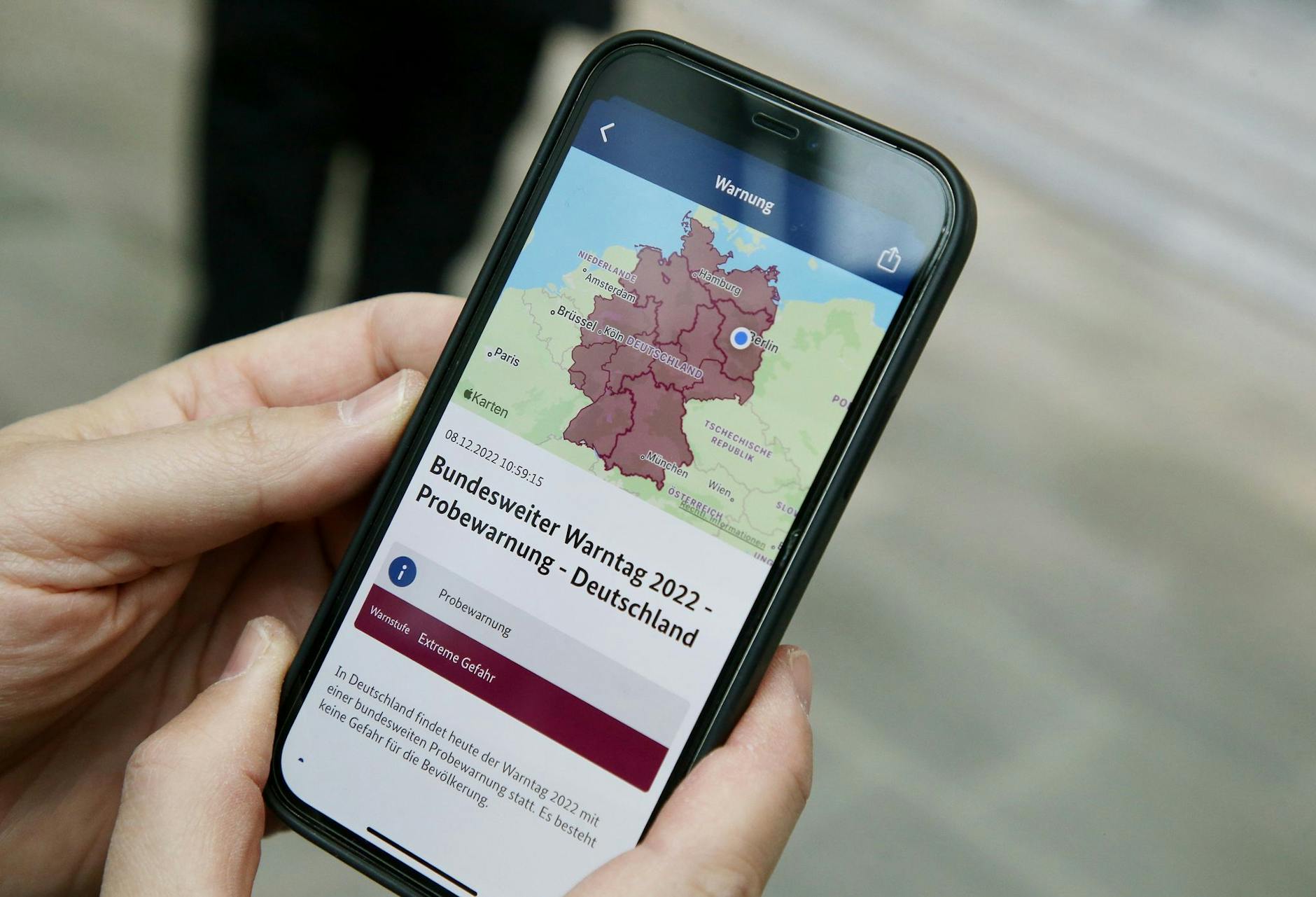 Ein Mitarbeiter des Bundeskanzleramts hält sein Mobiltelefon in der Hand.