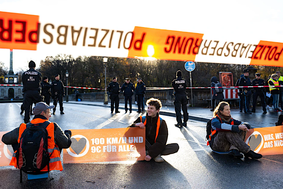 Klimaaktivisten der Letzten Generation sitzen auf der Prinzregentenstraße und blockieren den Verkehr. Ermittler haben bundesweit Räume der Gruppe durchsucht.&nbsp;