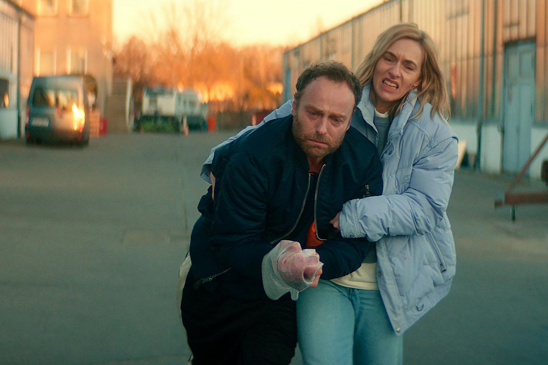 Ermittlungen mit schmerzhaften Folgen: Camilla (Kim Riedle) schleppt den verletzten Robert Karow (Mark Waschke) zum Auto. 