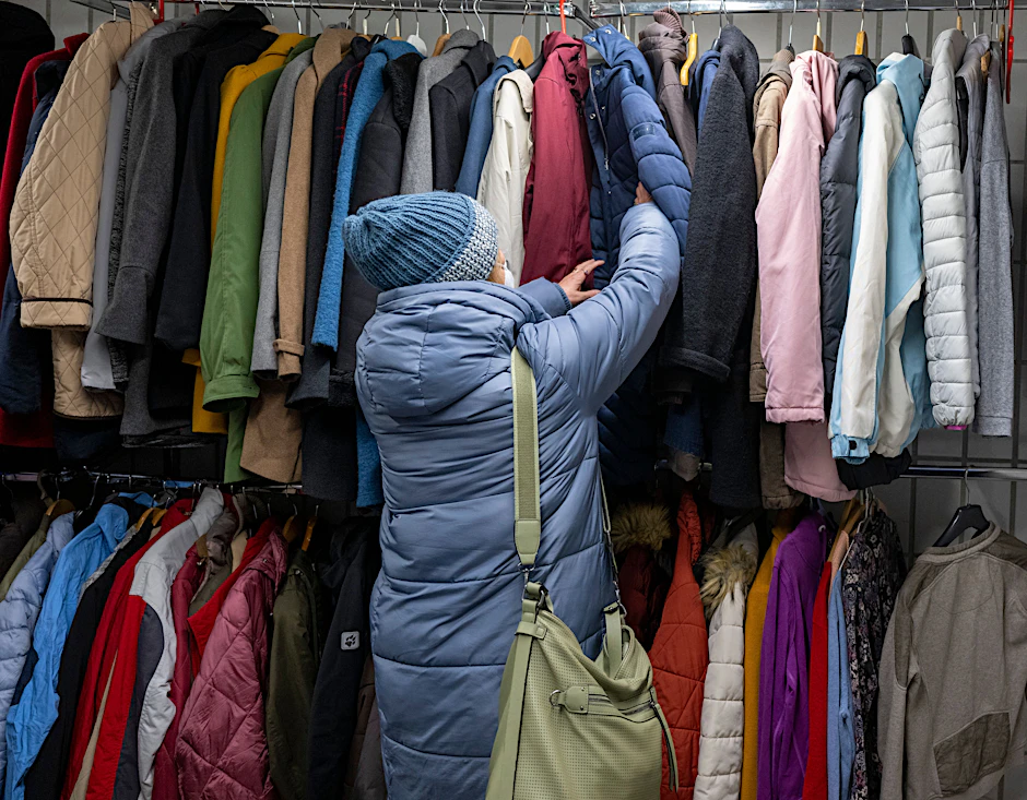 Berlin im Winter 2022: Eine Frau sucht in der Kleiderkammer der Berliner Stadtmission nach einer warmen Winterjacke.