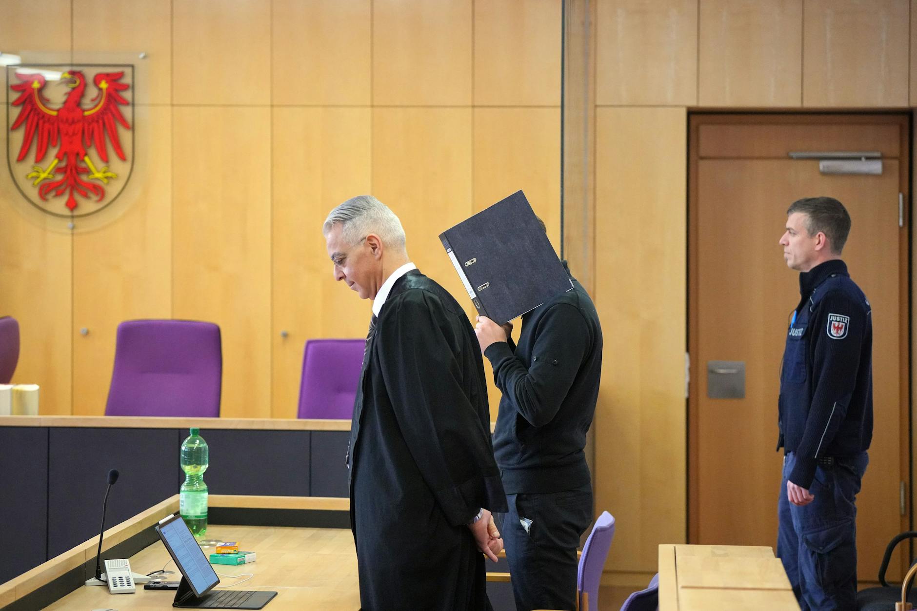 Vincent R. hält sich am Tag der Urteilsverkündung einen Aktenordner vors Gesicht, er will nicht fotografiert werden. An seiner Seite sein Anwalt Morad Sehouli.