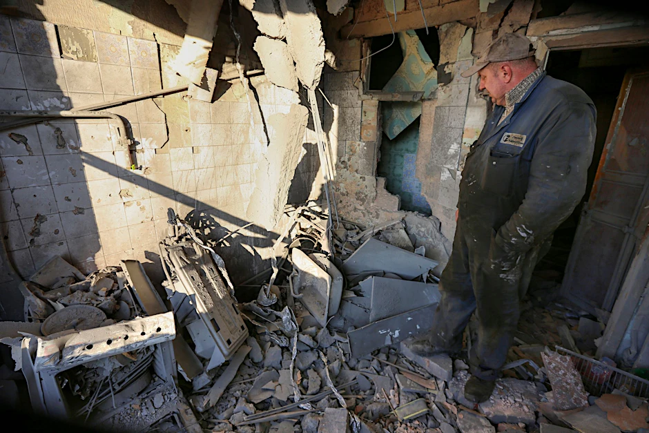 Ein Mann untersucht ein durch Beschuss beschädigtes Wohnhaus. Die Ukraine meldet erneut neue Raketenangriffe.  