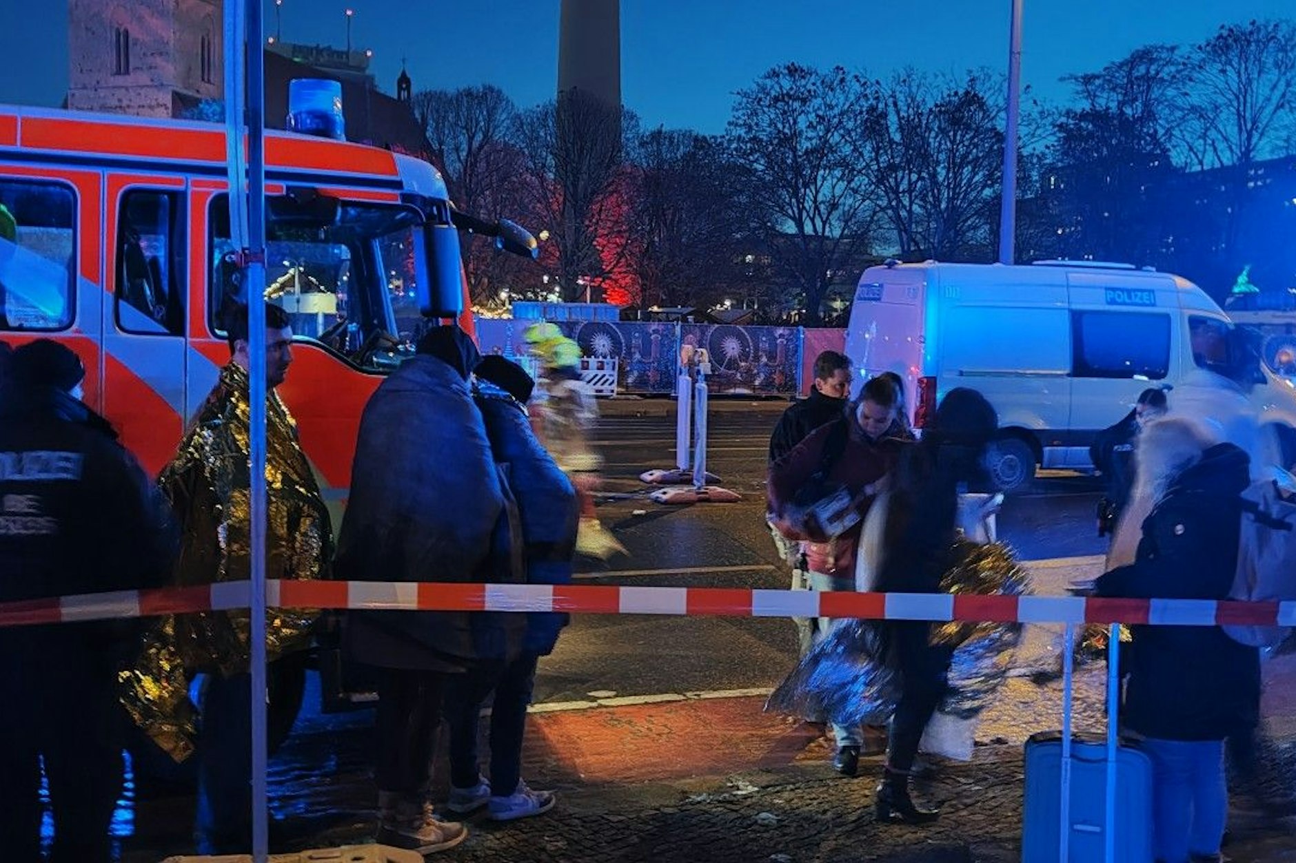Menschen stehen im Nahbereich des Hotels.  Einsatzkräfte sind vor Ort.