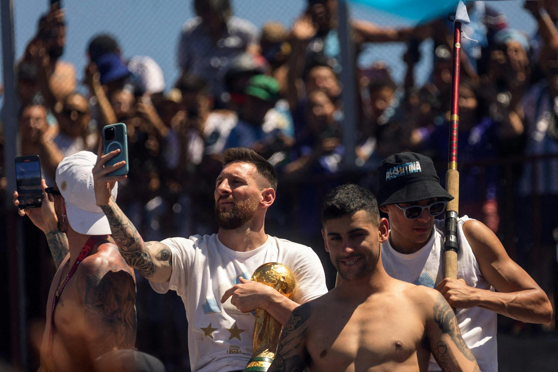 Mega-Star Lionel Messi (l.) macht bei den Feierlichkeiten in Buenos Aires ein Selfie - unterm Arm trägt er den WM-Pokal. 
