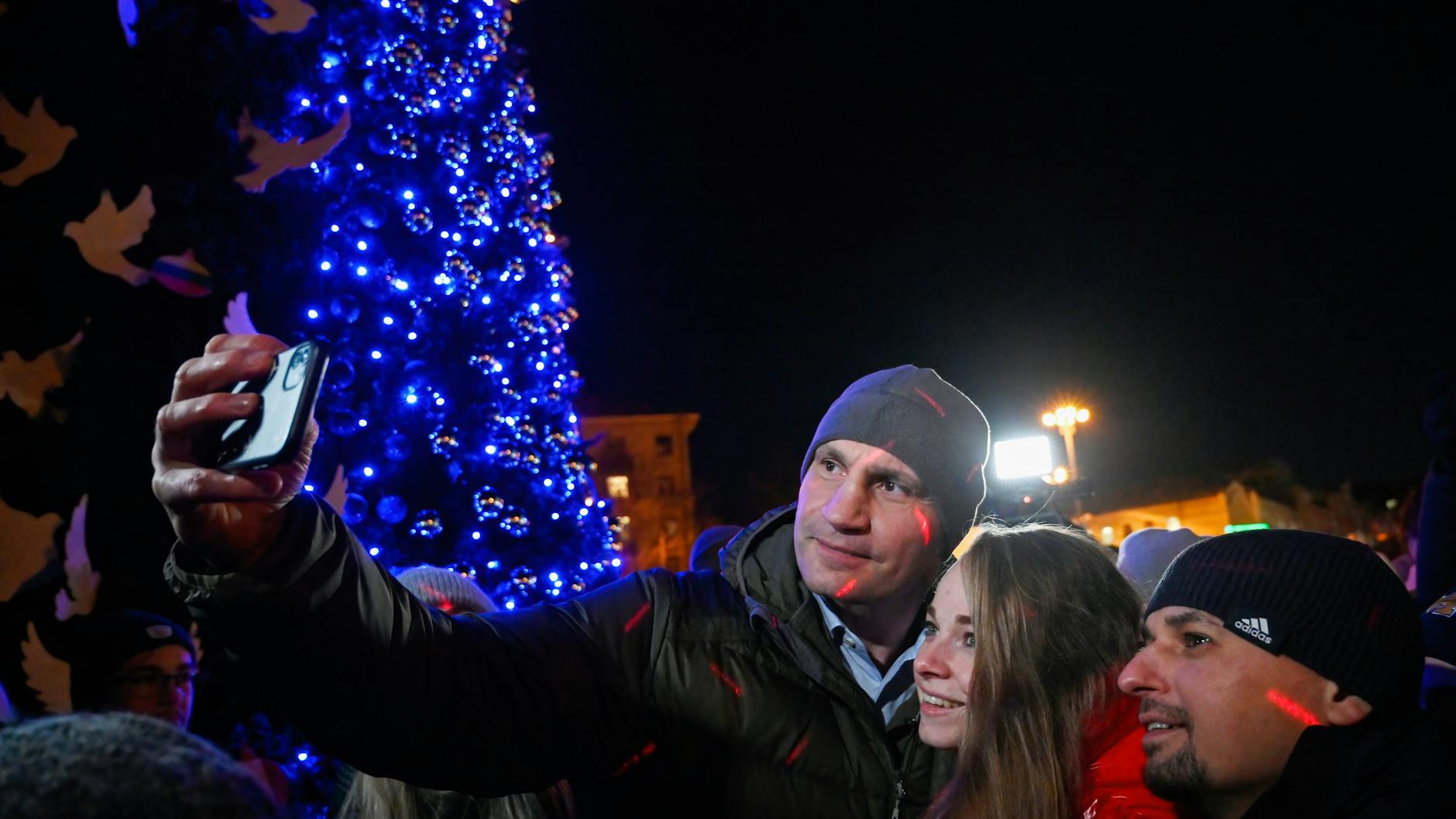Ein paar Tage vor Weihnachten: Vitali Klitschko (l), Bürgermeister von Kiew, macht ein Selfie mit Unterstützern während der Einweihung eines Weihnachtsbaums, der in den Farben der ukrainischen Nationalflagge geschmückt ist. In Kiew kommt es immer wieder zu Stromausfällen. 