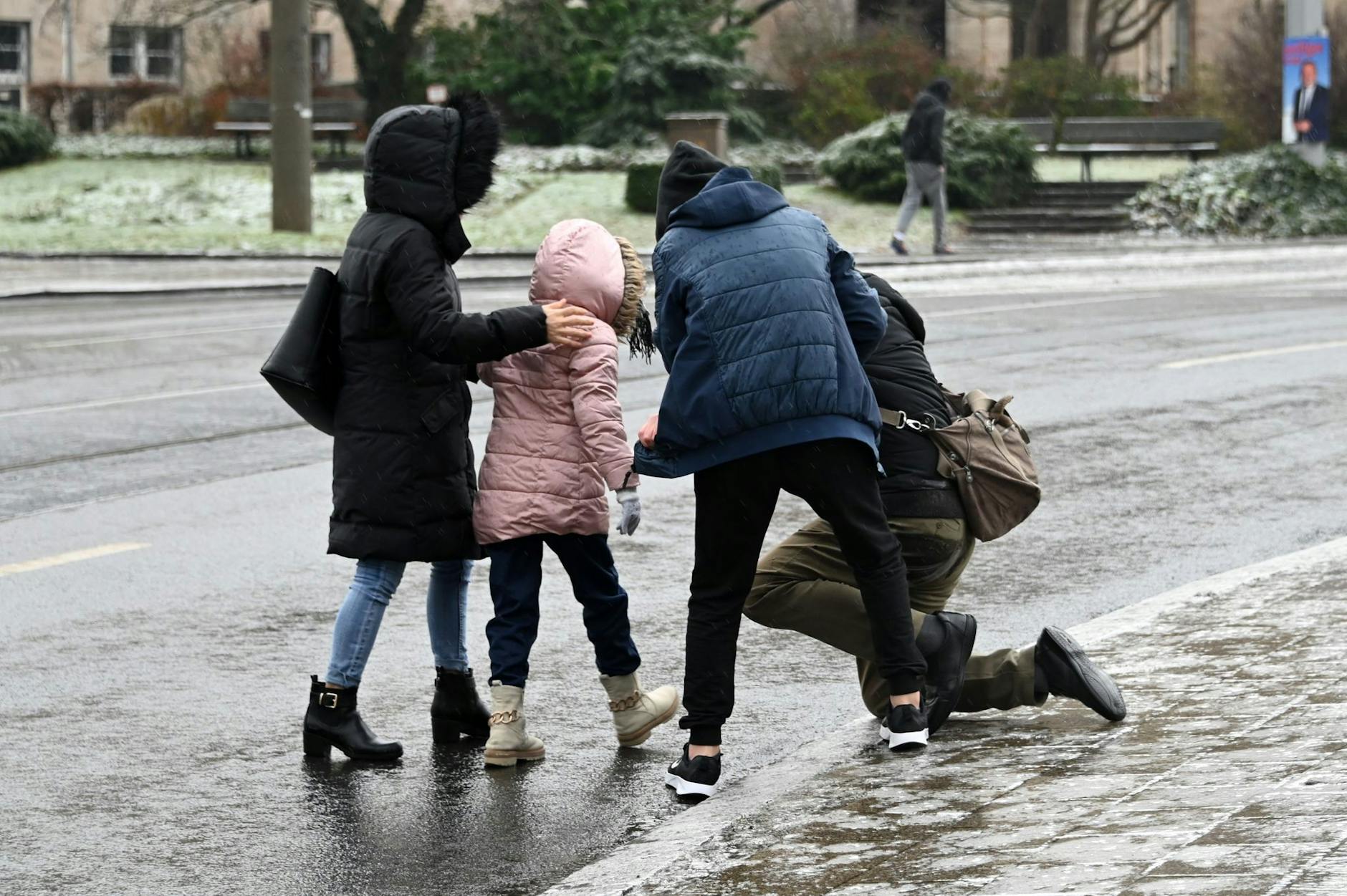 dpatopbilder - Einem Mann, der bei Eisglätte in Kassel vom Gehweg auf die Straße gestürzt ist, wird aufgeholfen.