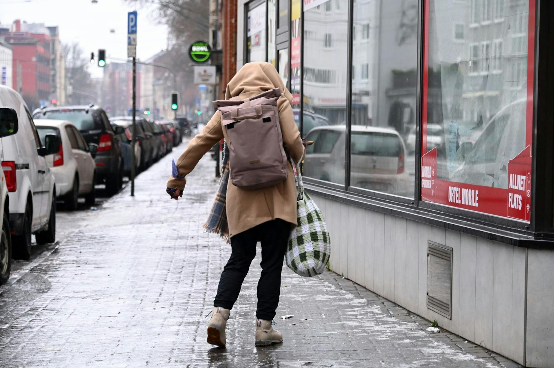 Eine Frau schlittert über den vereisten Gehweg in Kassel.