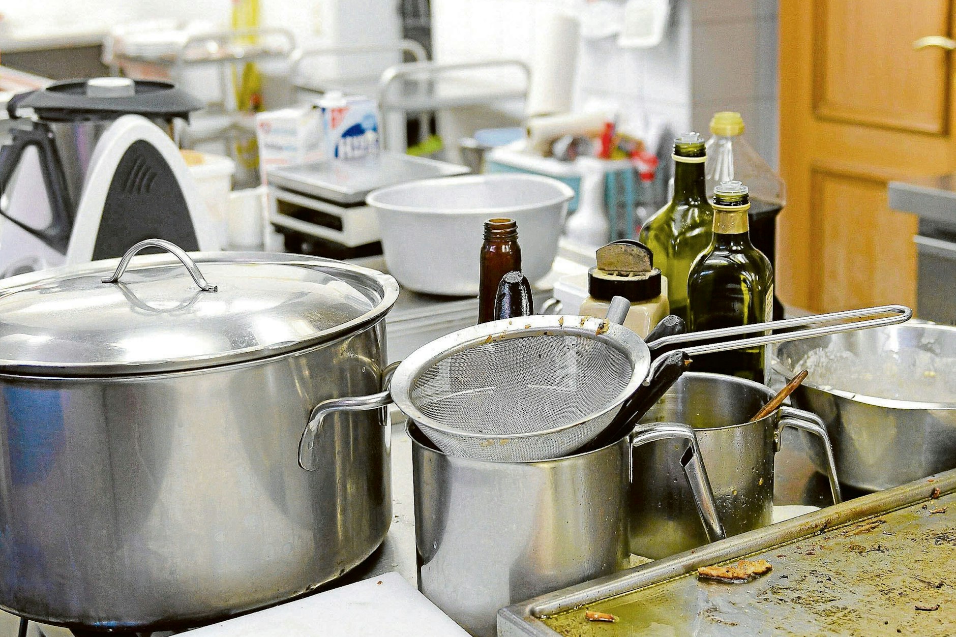 Töpfe, Siebe, Pfannen türmen sich auf einem Herd in einer Restaurantküche.