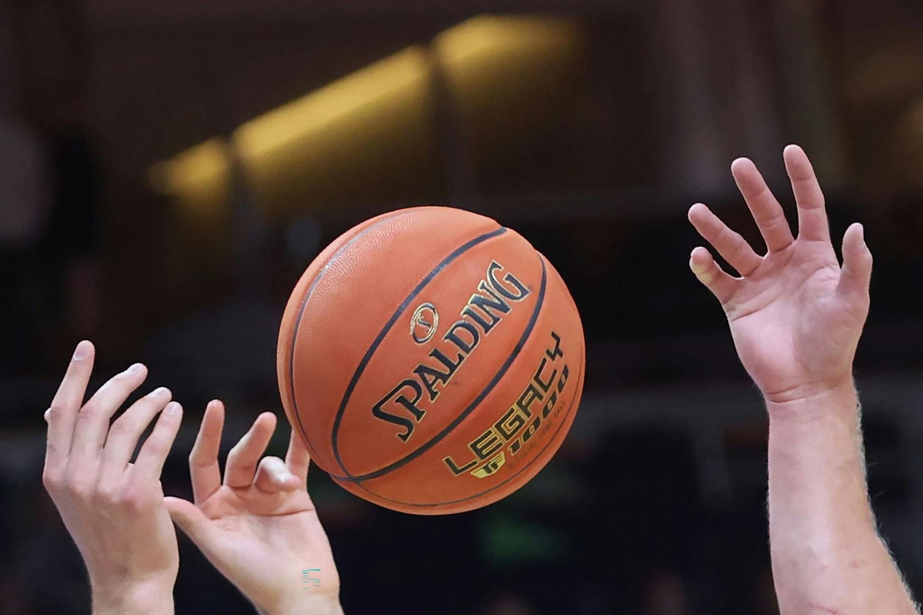 Spieler greifen nach einem Basketball.