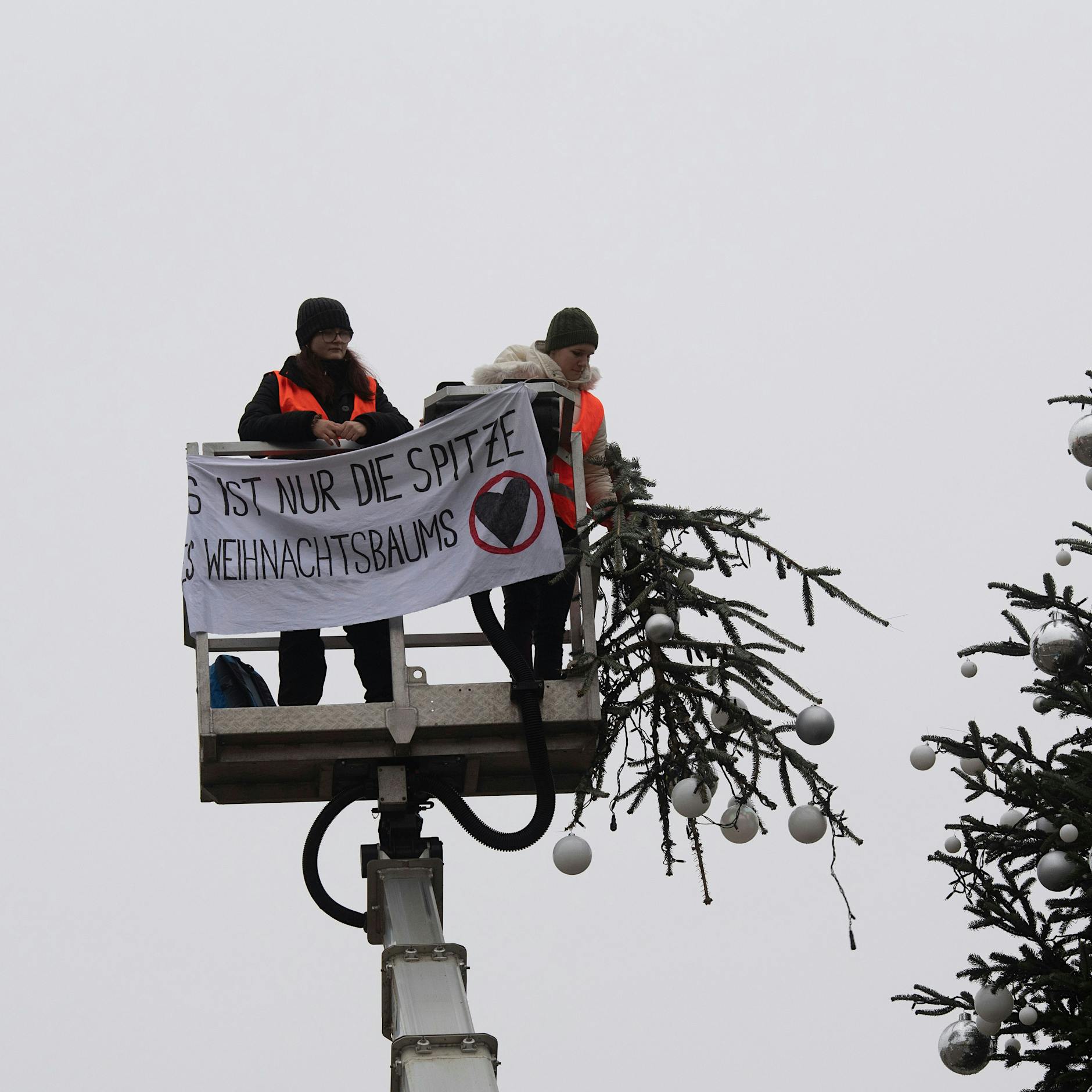 UPDATE Polizisten merkten zuerst nicht, was da los war: Jetzt wird gesägt statt geklebt - Klima-Kleber kappen Weihnachtsbaumspitze am Brandenburger Tor