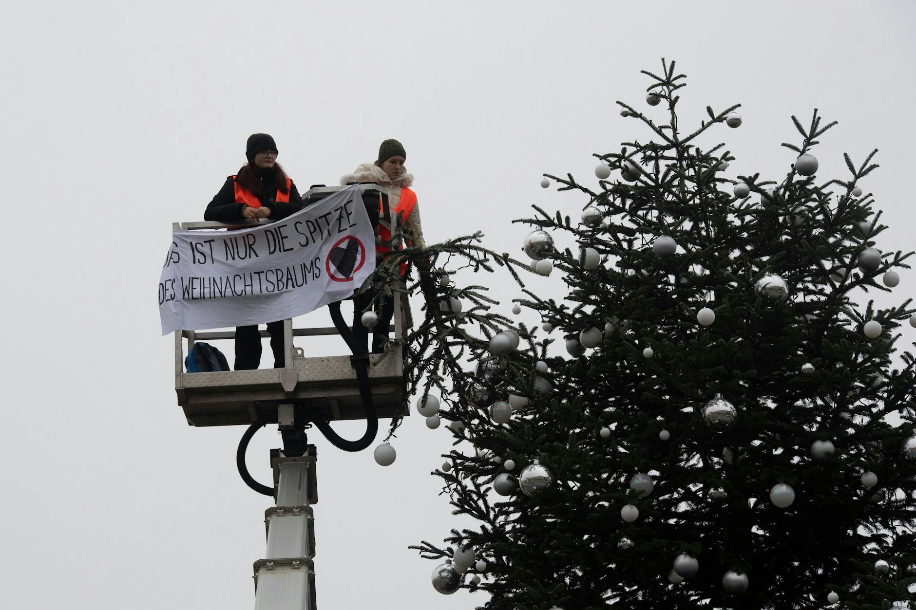 Klima-Aktivisten sägen die Spitze des Weihnachtsbaumes am Brandenburger Tor ab - und die Polizei vor Ort greift nicht ein.