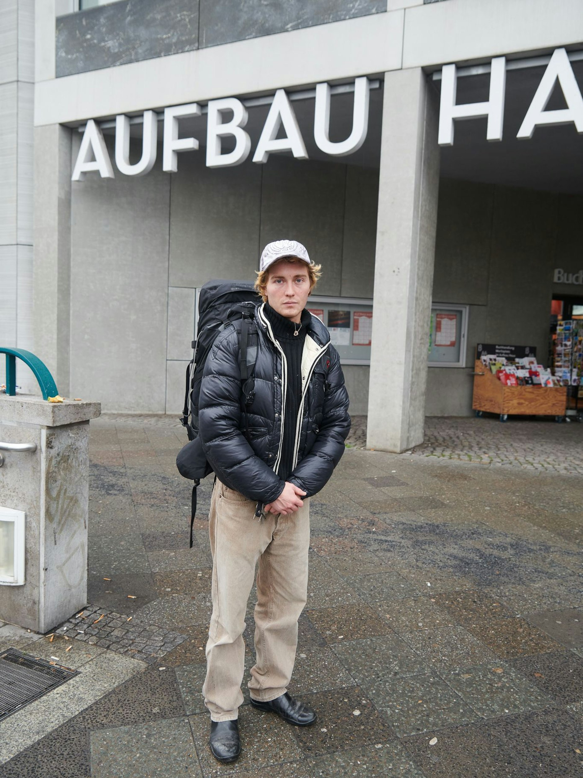 Laurids ist kein Reisender, sondern Student der Bildhauerei an der Kunsthochschule Berlin-Weißensee, der im Rucksack sein Werkzeug trägt. Heute wird er seinen Modulor-Gutschein einlösen. Sein wetterfestes Outfit: Jacke von Moncler, Rolli von Ralph Lauren, Hose von Marlboro Classics, Stiefeletten von Prada (alles secondhand gekauft). Dazu trägt er ein Cap des litauischen Labels Urte Kat.&nbsp;&nbsp;