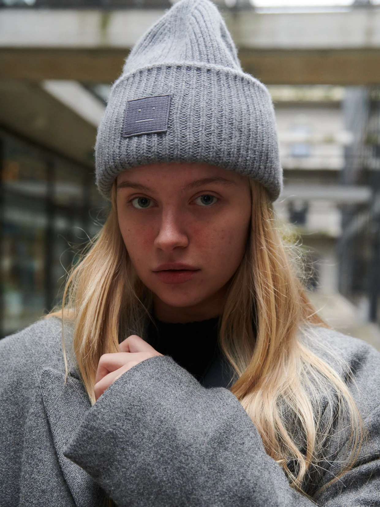 Karina trägt eine Mütze von Acne Studios und einen langen Mantel von Zara.
