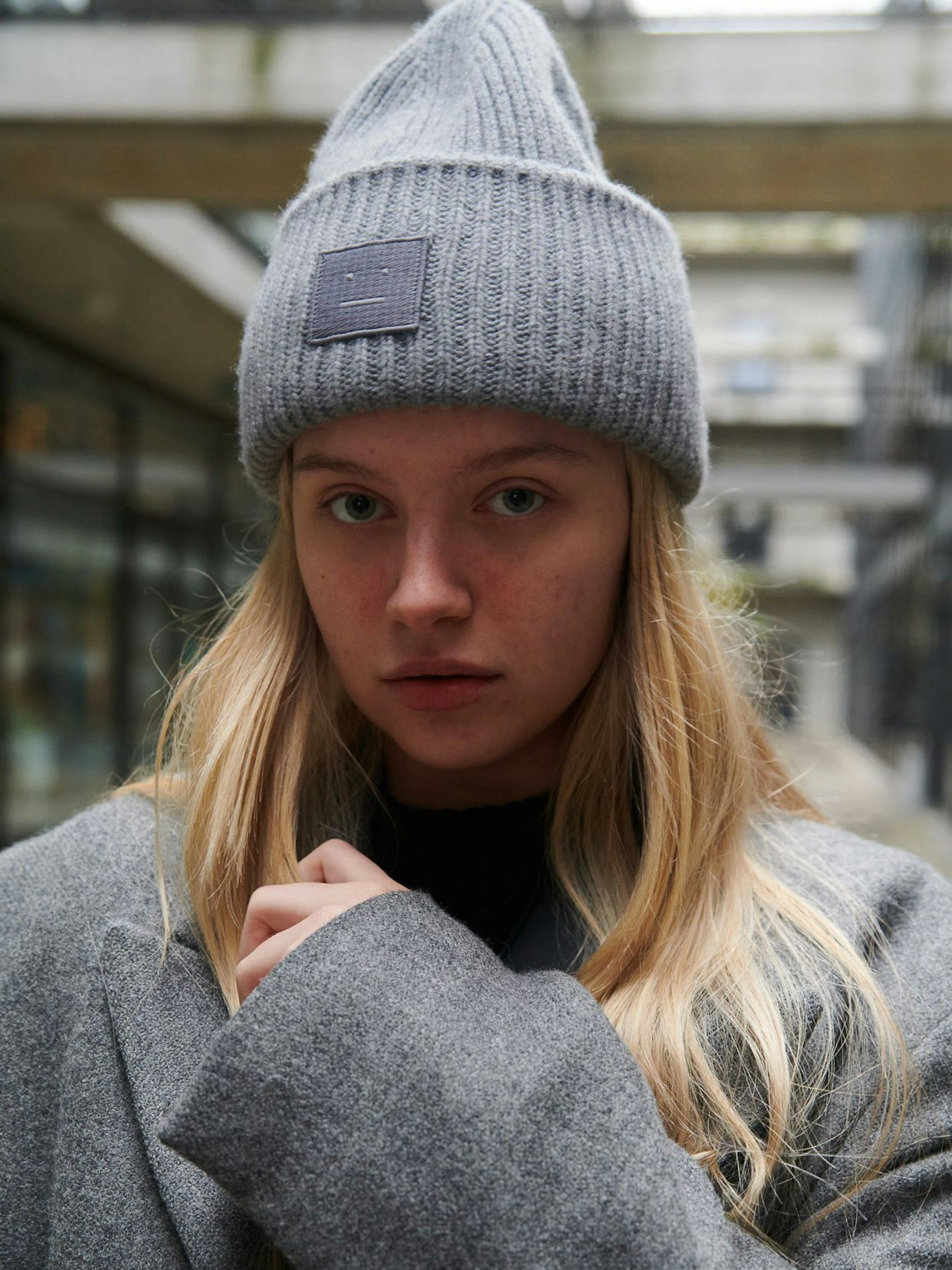 Karina trägt eine Mütze von Acne Studios und einen langen Mantel von Zara.