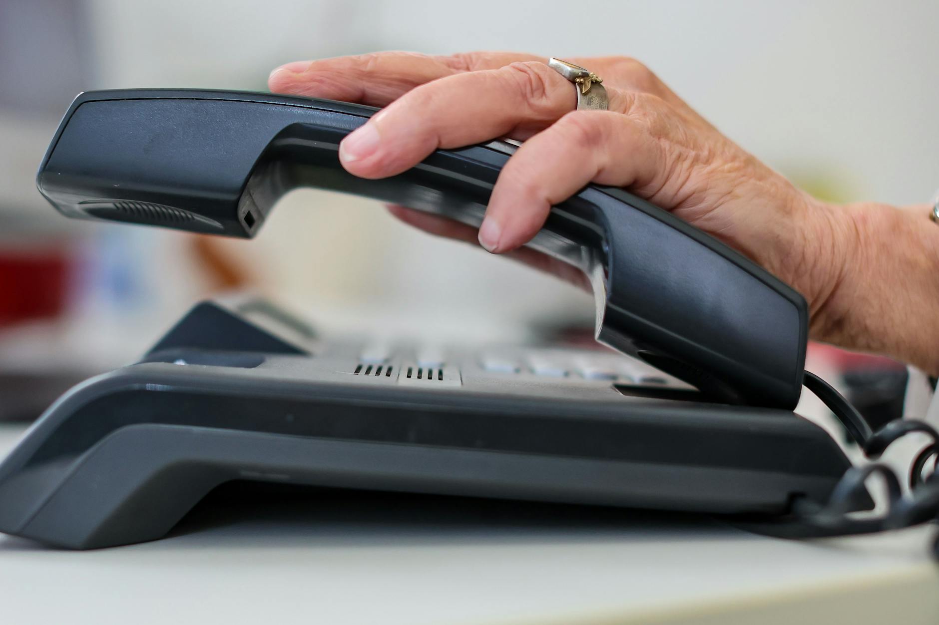 Eine Mitarbeiterin der Telefonseelsorge nimmt einen Telefonhörer an ihrem Arbeitsplatz in die Hand.