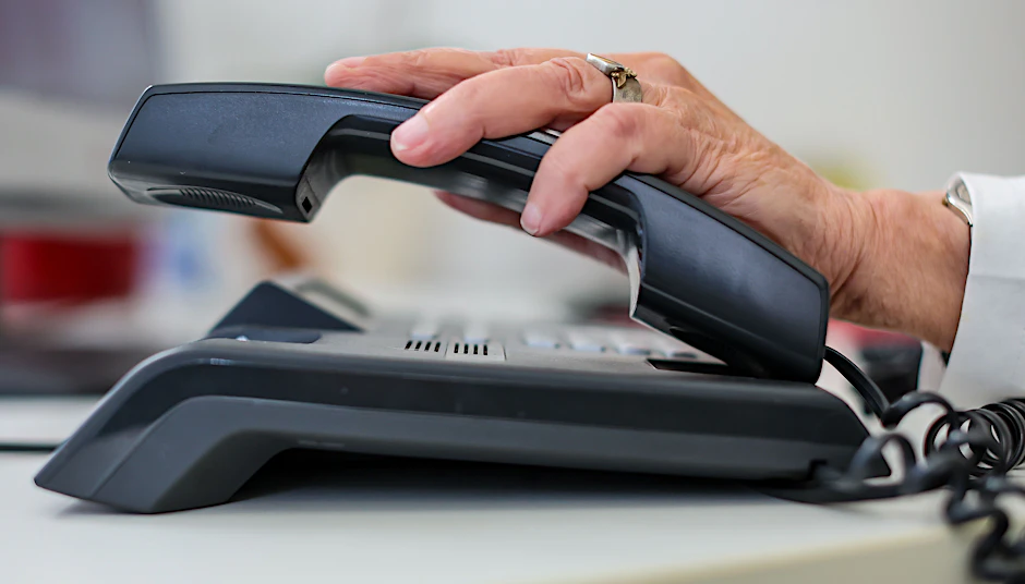 Eine Mitarbeiterin der Telefonseelsorge nimmt einen Telefonhörer an ihrem Arbeitsplatz in die Hand.