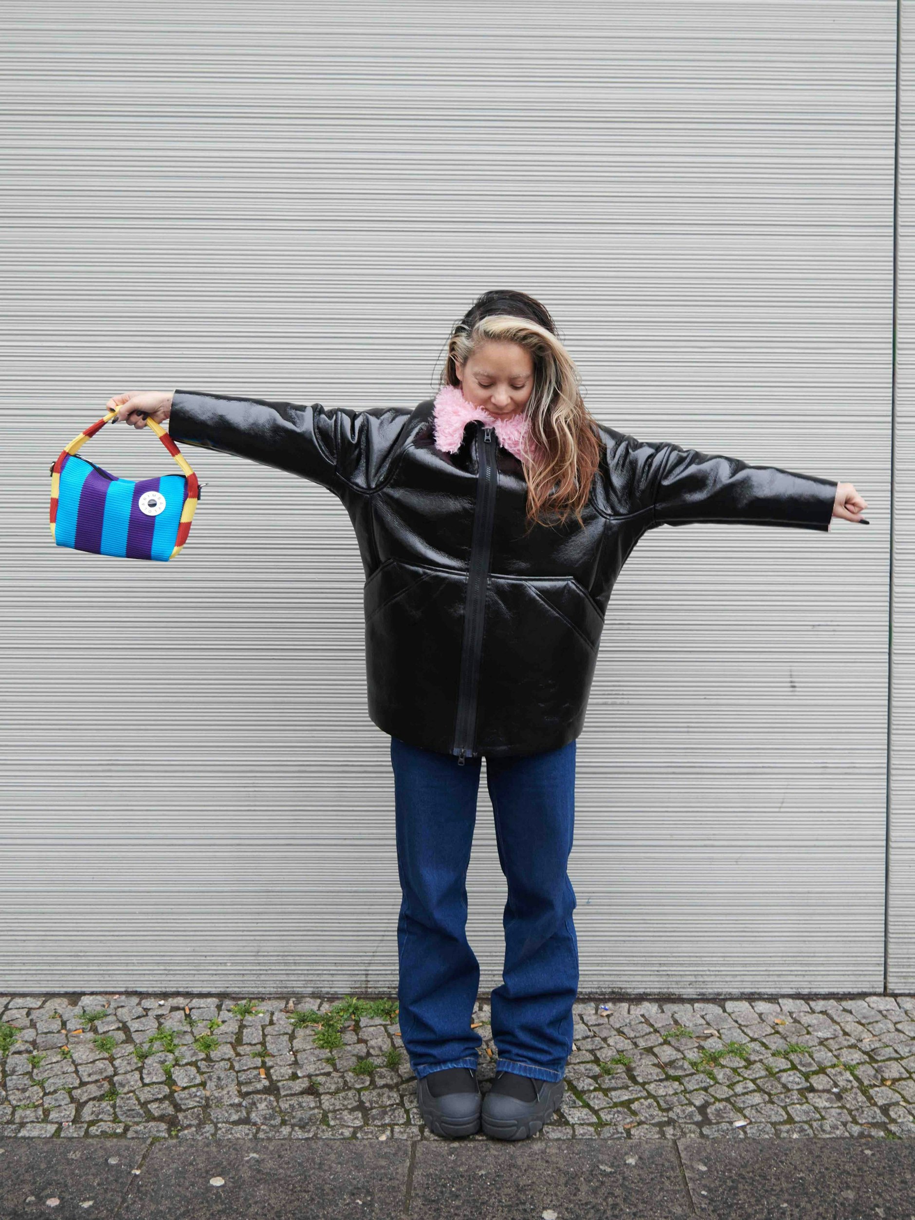 Mika ist Unternehmerin. Als Inhaberin der PR-Agentur Moriyama Projects mit Sitz im Aufbau Haus betreut sie vor allem Kunden aus der Fashionbranche. Sie trägt eine vegane Lacklederjacke mit rosa Plüschfutter von Bimba Y Lola und eine Bootcut-Jeans von Karl Kani.&nbsp;