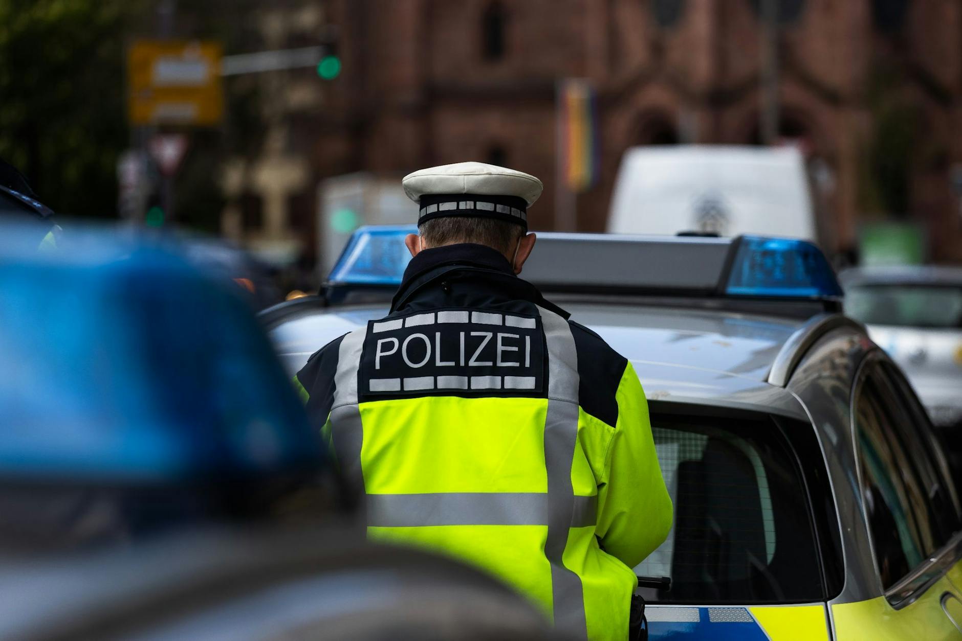 ARCHIV - Ein Polizeibeamter steht zwischen zwei Einsatzfahrzeugen der Polizei. ild