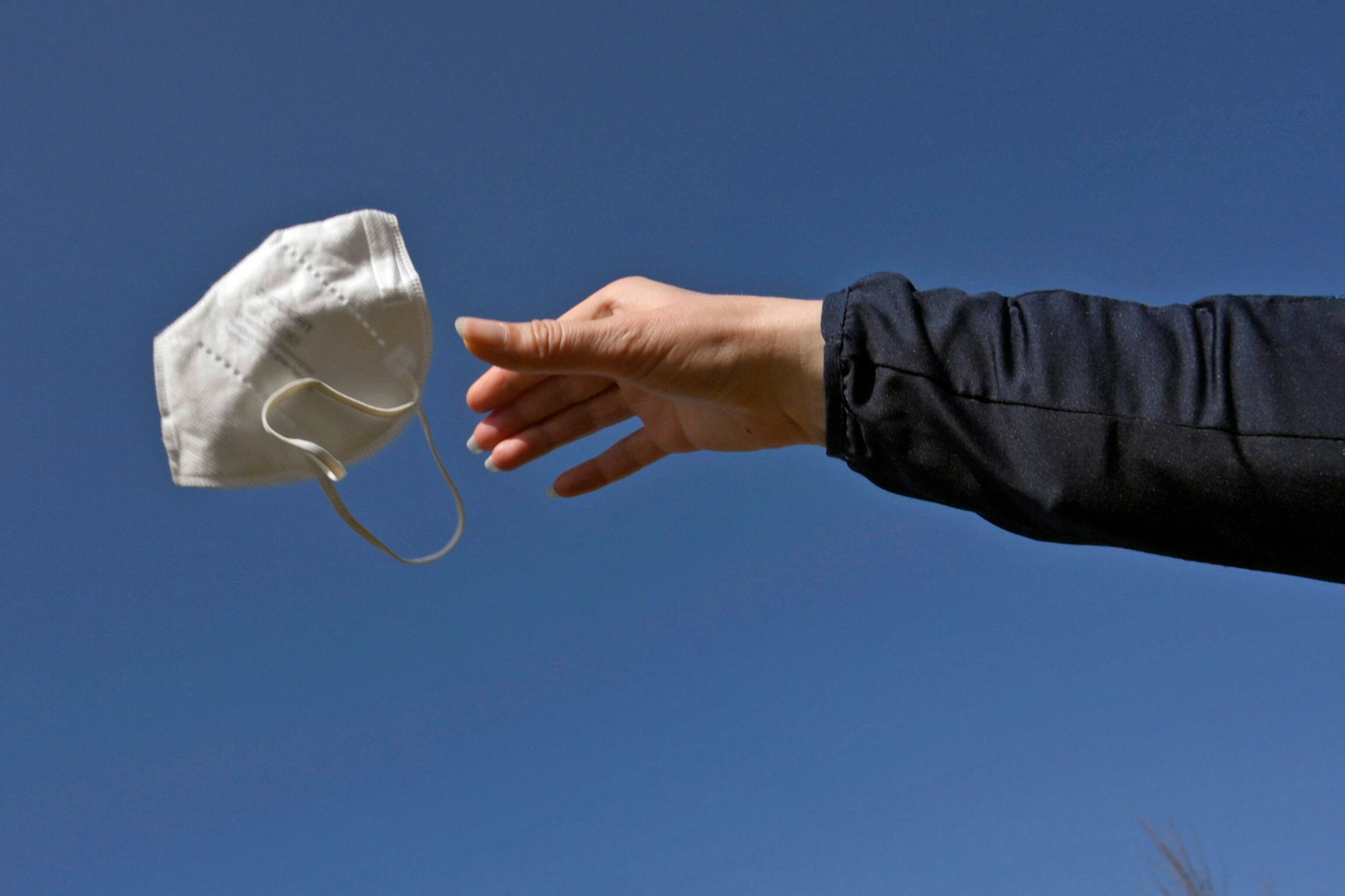 Eine Frau wirft ihre FFP2-Maske weg – bald soll die Maskenpflicht enden.