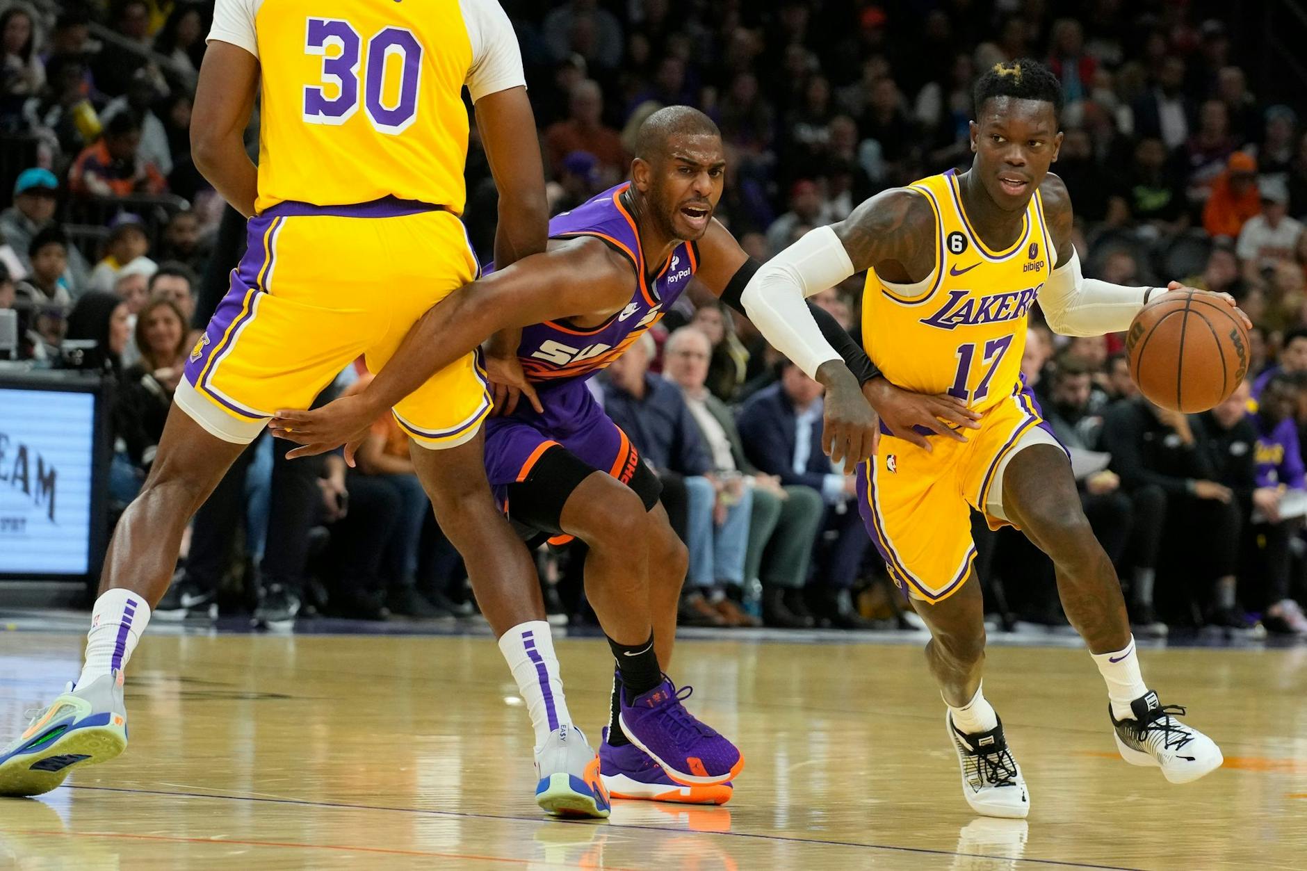 Lakers-Guard Dennis Schröder (17) zieht an Suns-Guard Chris Paul (M) vorbei, während Lakers-Center Damian Jones (30) einen Pick setzt.