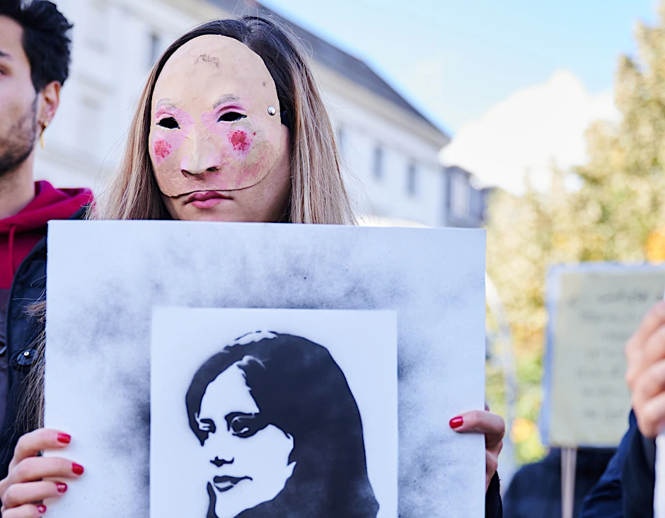 ARCHIV - Eine Demonstrantin hält in Berlin eine Abbildung der getöteten Kurdin Jina Mahsa Amini in die Höhe.  