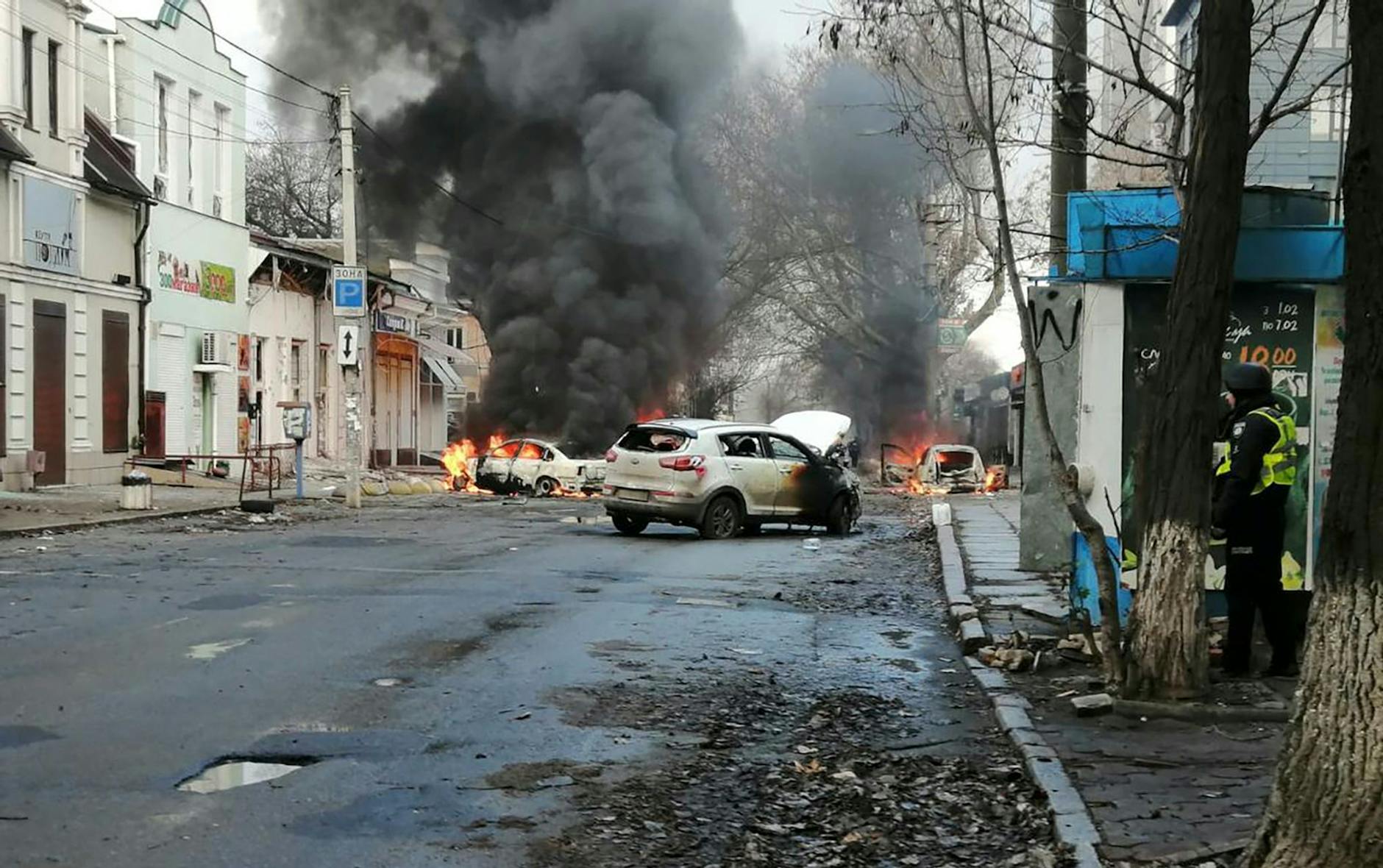 Autos brennen nach einem russischen Raketenangriff auf das Stadtzentrum von Cherson. /dpa