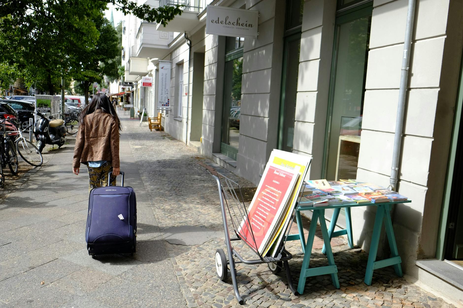 Eine Person scheppert mit einem Rollkoffer durch Prenzlauer Berg.