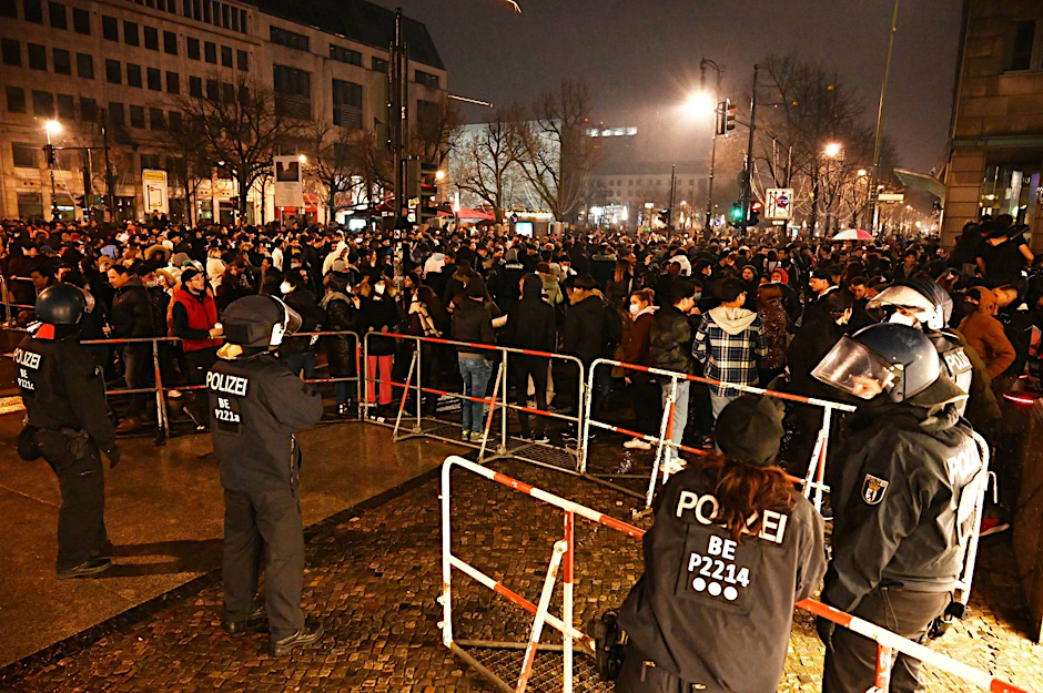ARCHIV - Polizisten stehen in der Silvesternacht 2021 hinter einer Absperrung am Brandenburger Tor.  