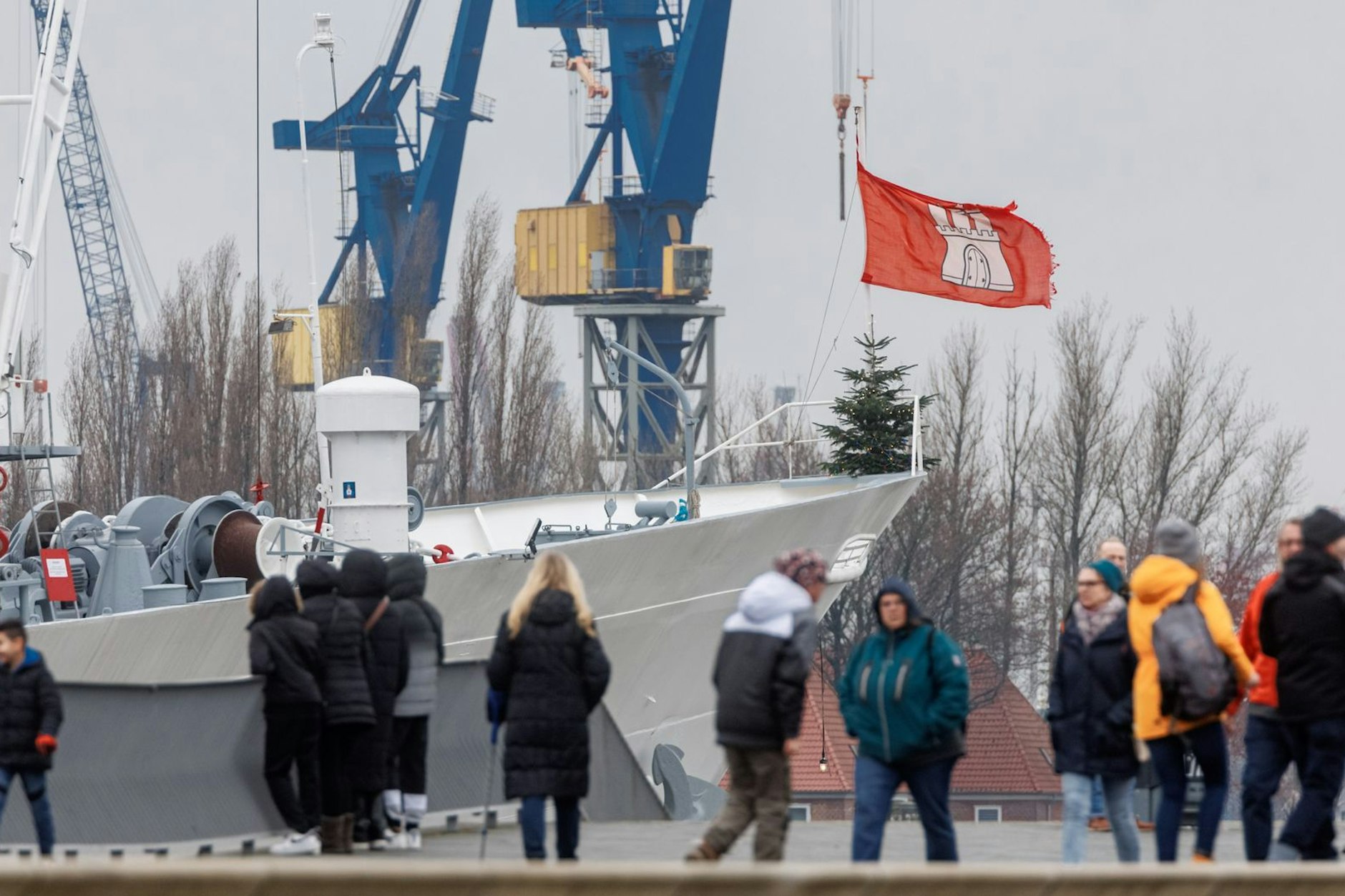 Passanten spazieren bei wechselhaftem Wetter am Hafen in Hamburg.