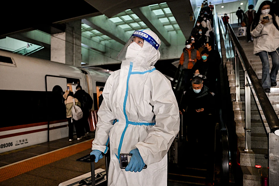 Ein Fahrgast mit Schutzausrüstung steht in einem Bahnhof in Peking. Die USA und Italien führen eine Testpflicht für Einreisende aus China ein.