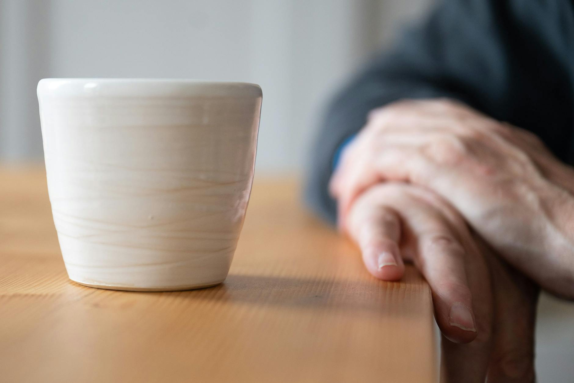Ein Mann sitzt neben einer hangetöpferten Kaffeetasse mit Kaffee. Weniger Stress - dieser Wunsch für das kommende Jahr ist laut einer Umfrage im Auftrag der DAK-Gesundheit so verbreitet wie noch nie.