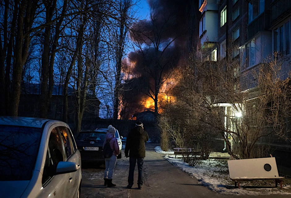 Anwohner beobachten ein brennendes Gebäude in Kiew, das bei einem Drohnenangriff getroffen wurde.